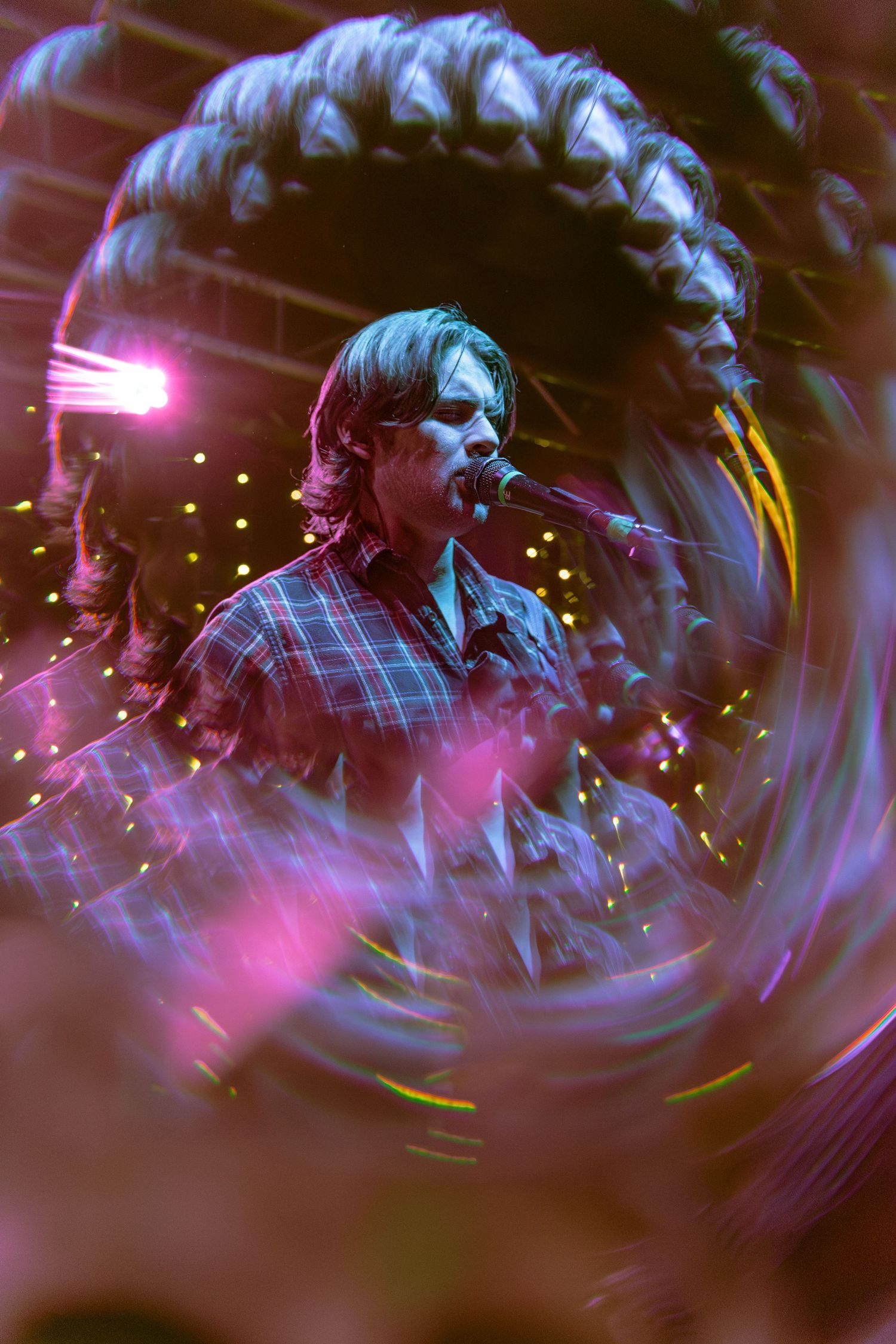 A musician performs on stage with motion blur effects and pink and blue lighting creating a dynamic atmosphere.