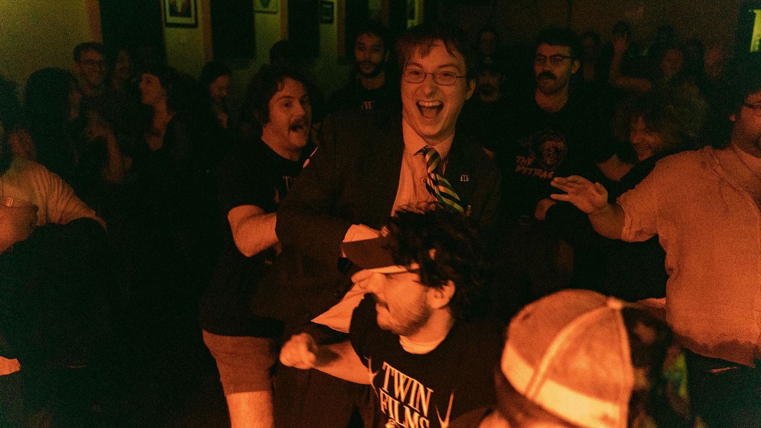 Concert crowd reacting enthusiastically in a dimly lit venue during a live performance.