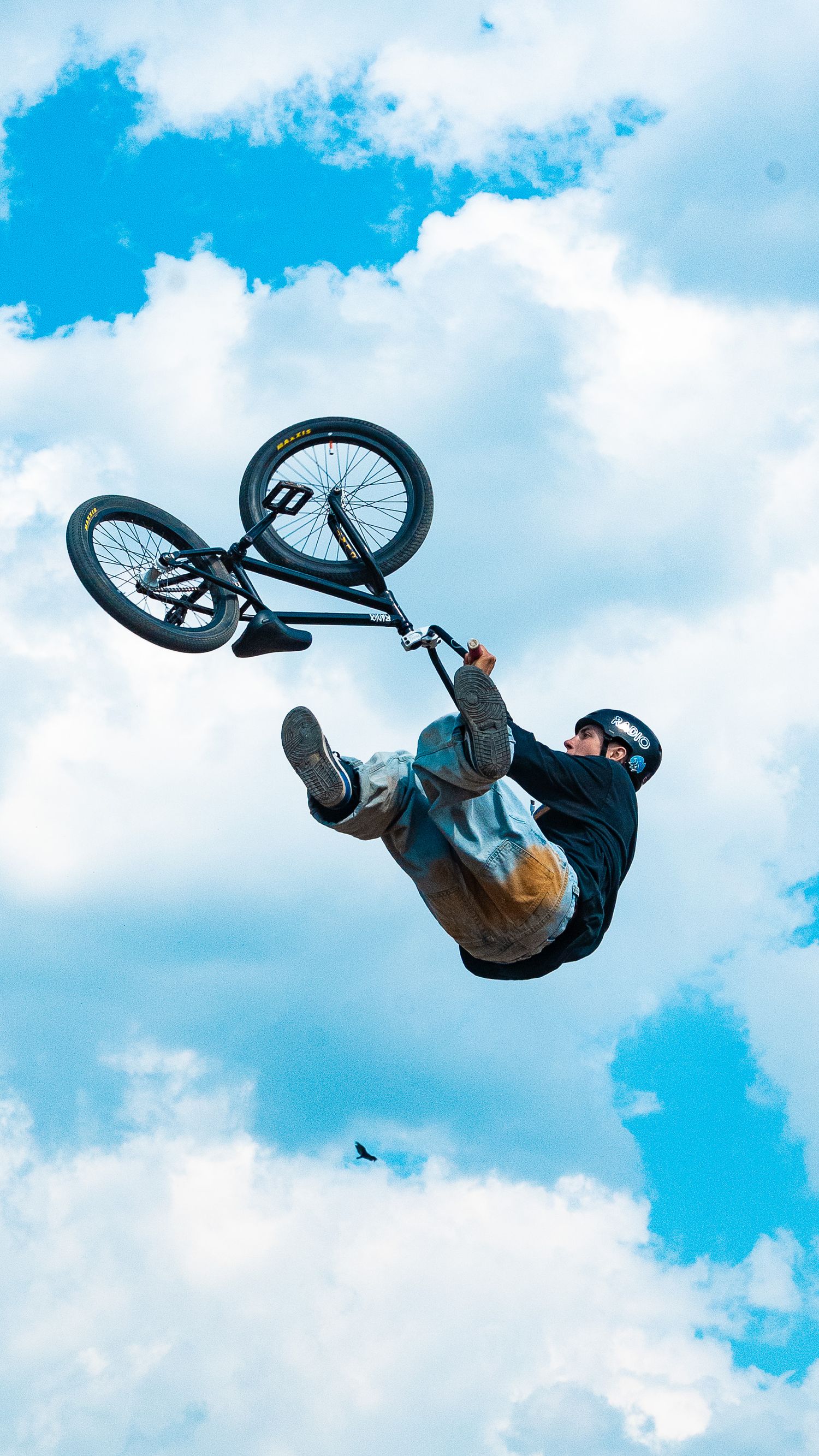 BMX rider executes an inverted aerial trick with bike rotation in mid-air.