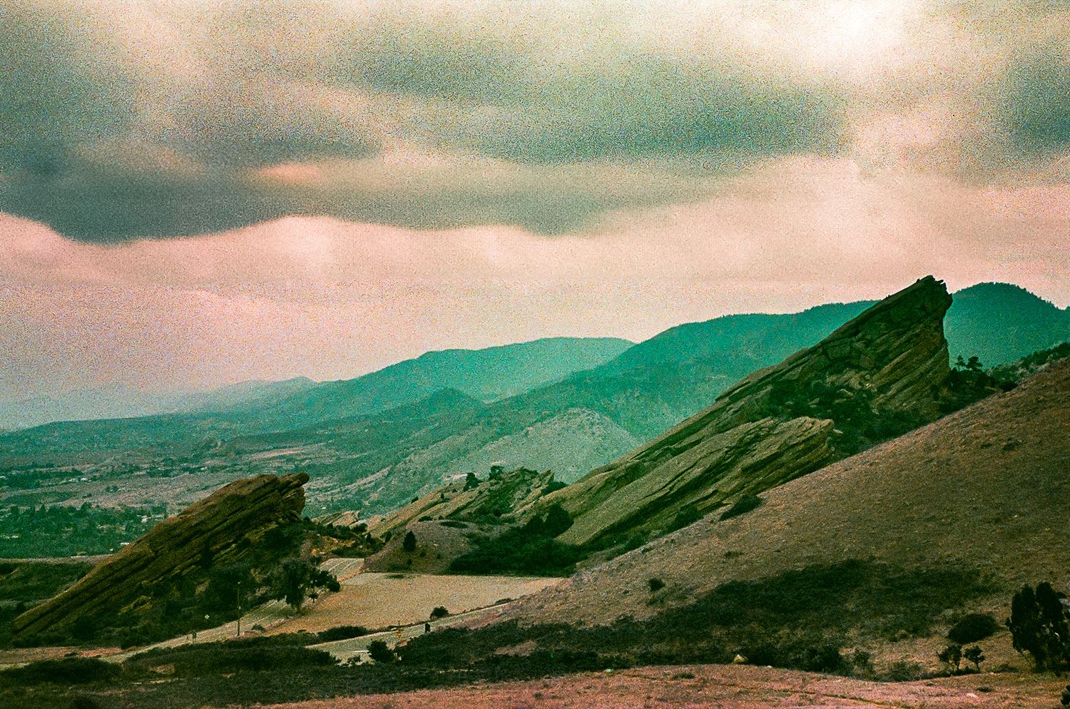 Vintage-style photograph of rolling green mountains under moody turquoise skies.