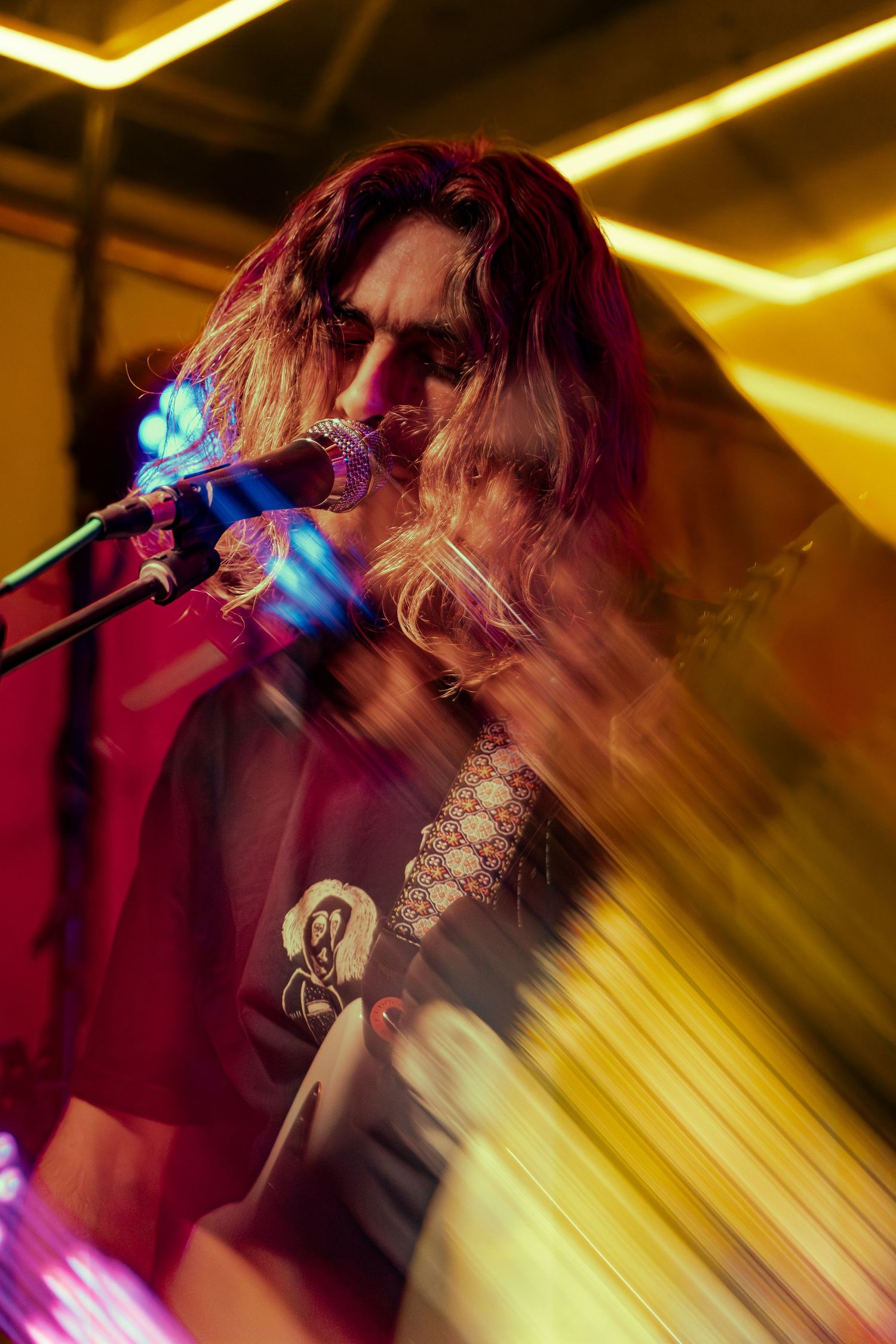 Concert performance under golden stage lighting with dramatic motion blur creating an energetic atmosphere.