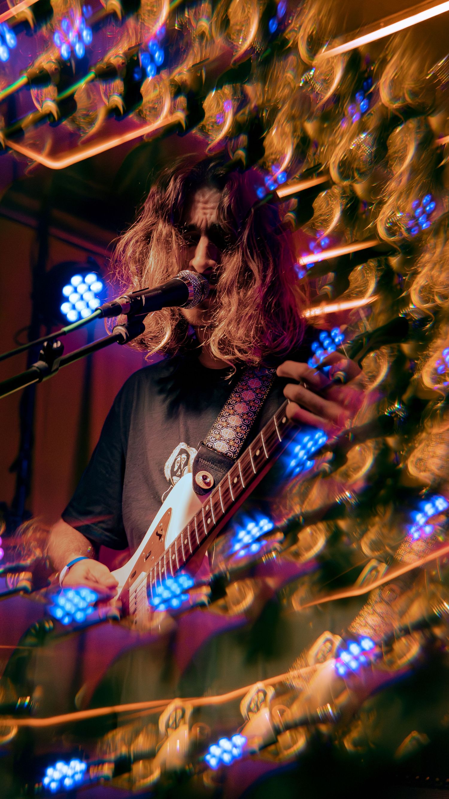 Rock musician performing on stage with blue stage lights and motion blur effects creating a dynamic atmosphere.