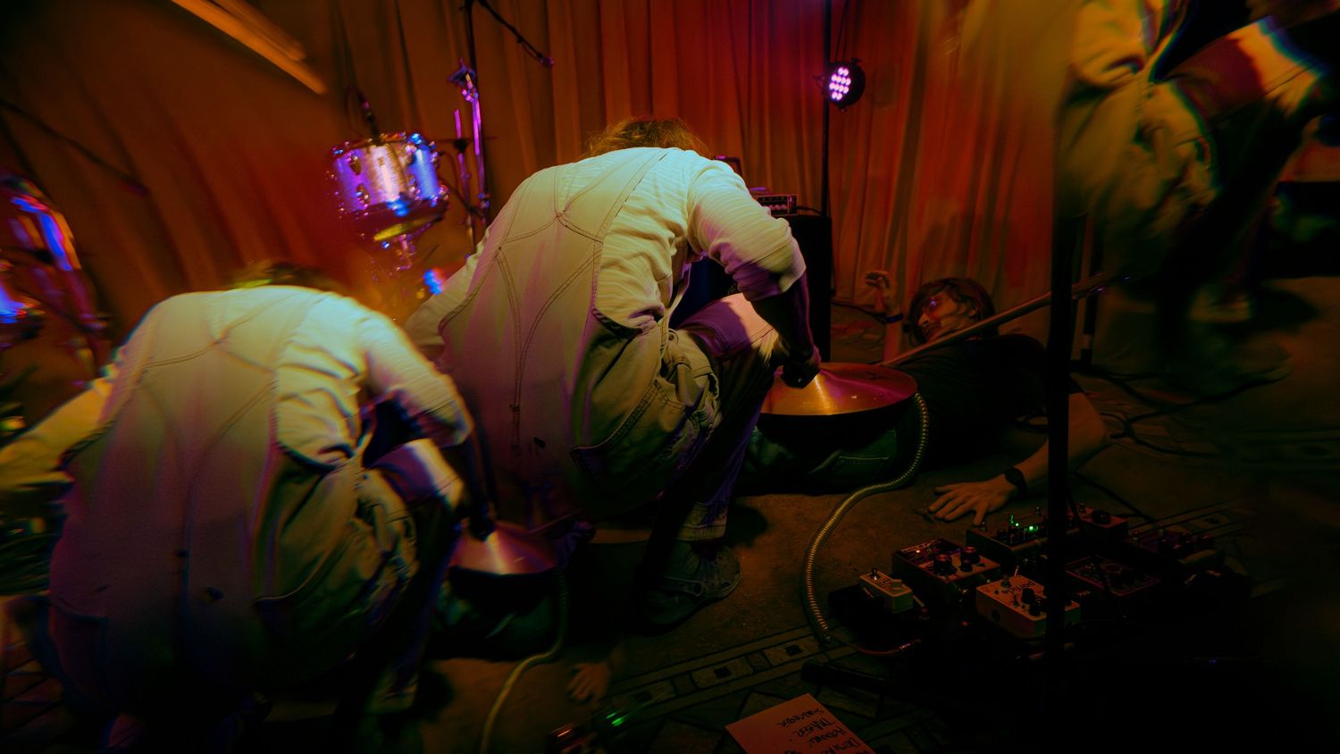 Three figures in hazmat suits work in an eerie red-lit environment during what appears to be a decontamination operation.