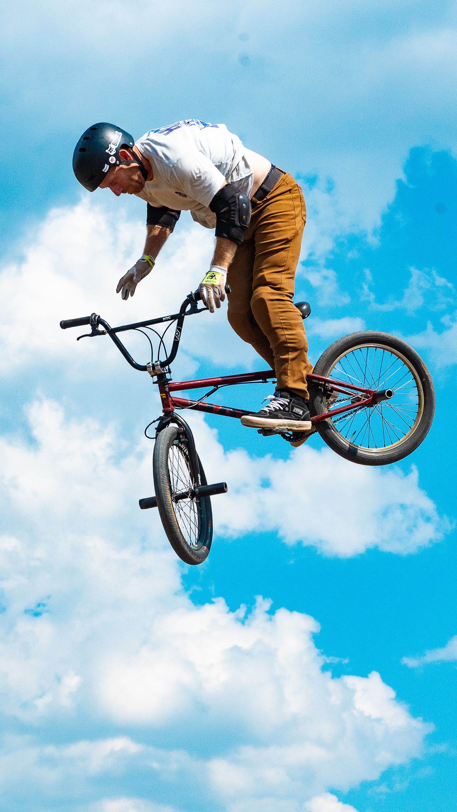 BMX athlete executes dramatic sideways stunt with bike in mid-air.