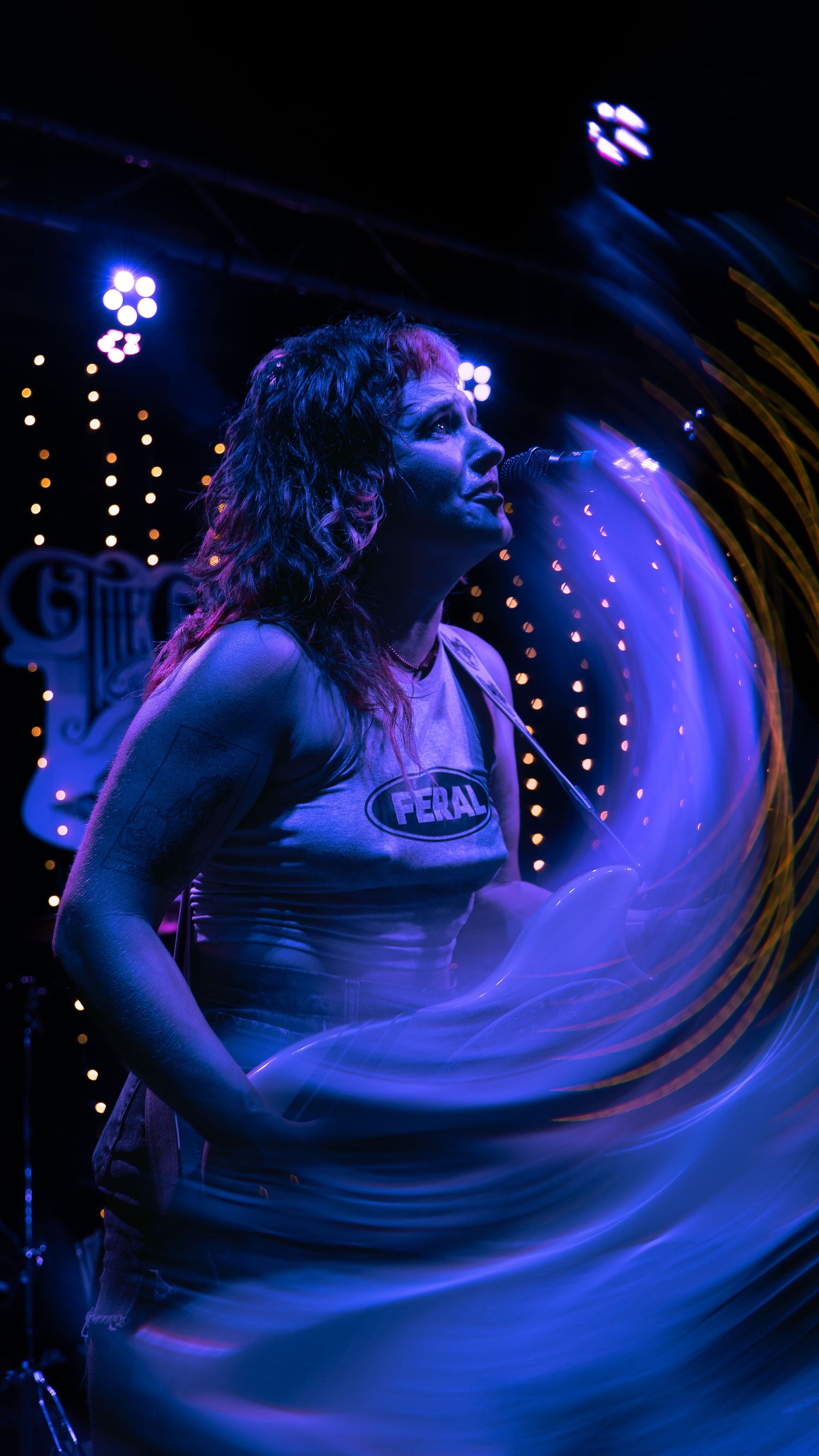 A dancer moves energetically in a blue-lit performance space creating spiraling motion trails in this artistic photograph.