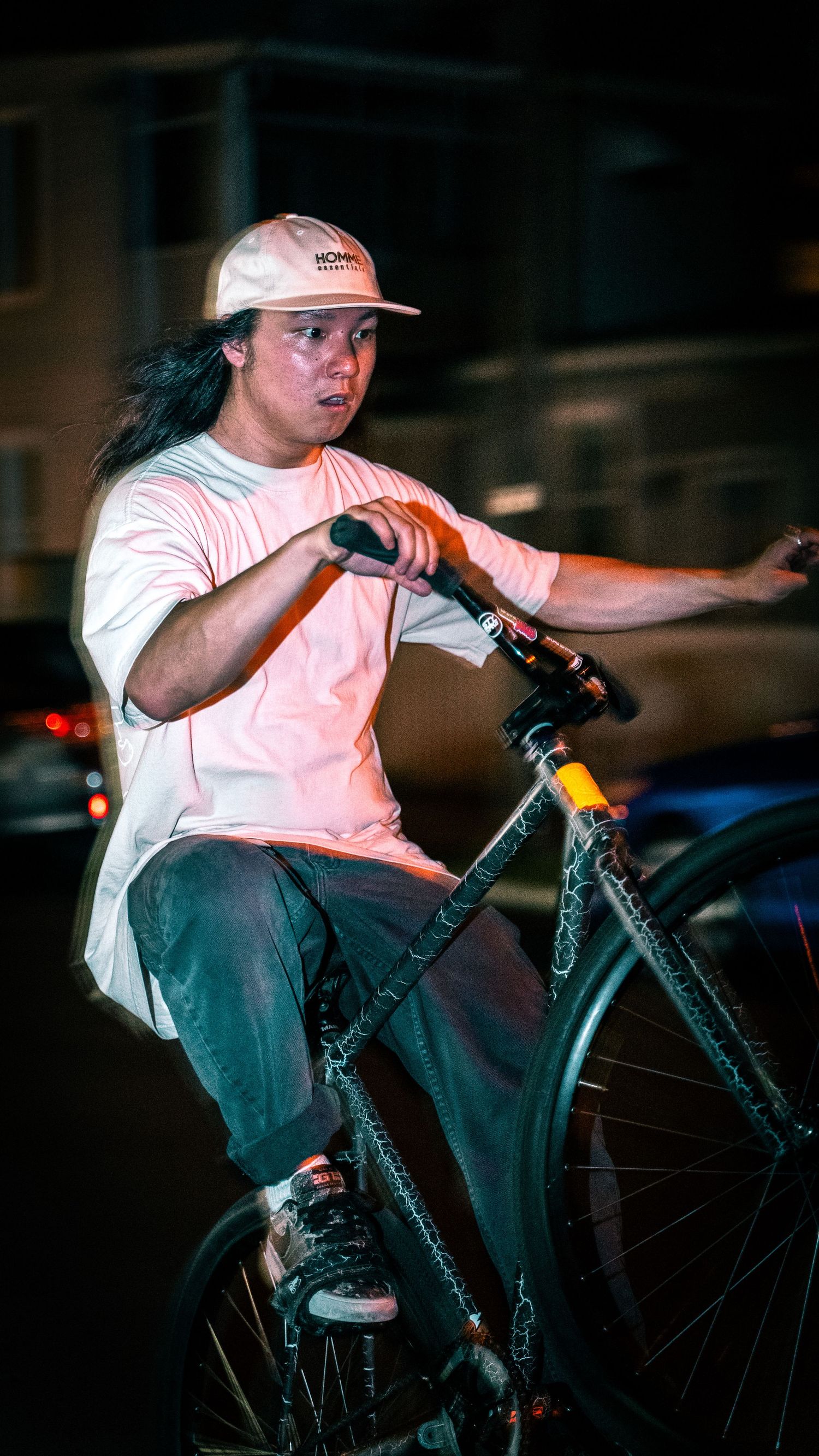 BMX rider performing tricks at night while wearing a white t-shirt and baseball cap.