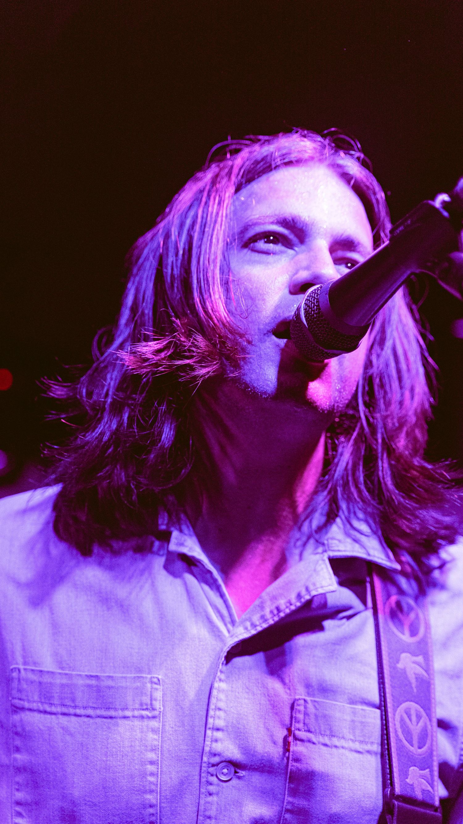Close-up performance shots with dramatic purple lighting and denim jacket.