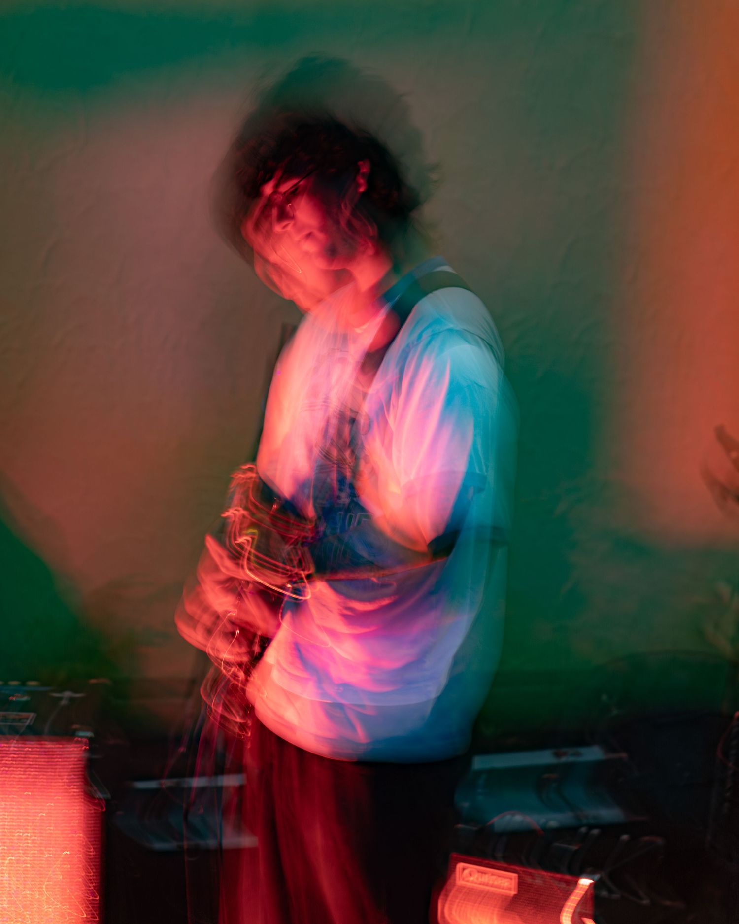 Motion-blurred concert performer bathed in dramatic red and blue stage lighting creates ethereal effect.