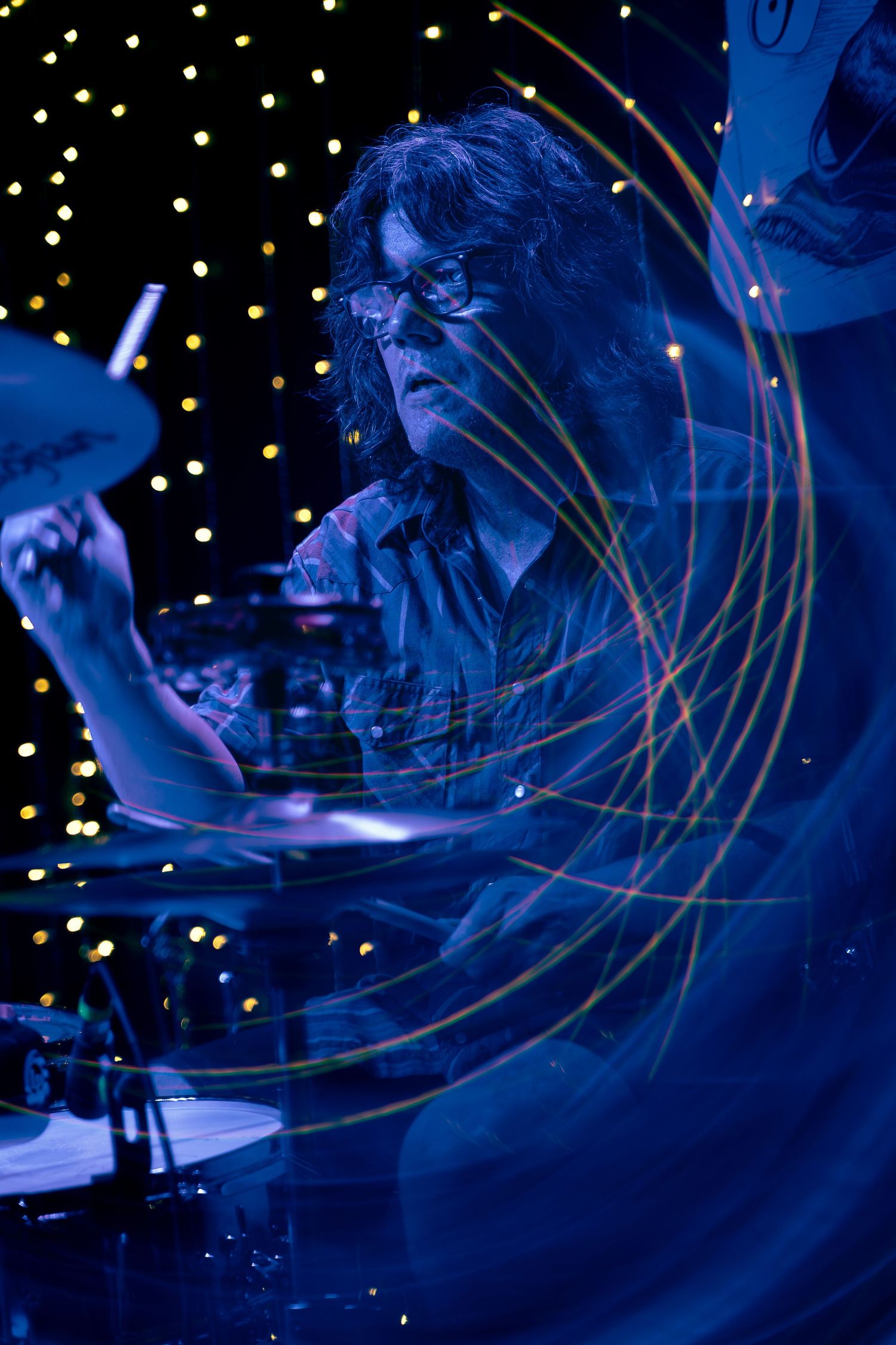 A musician performs on stage bathed in atmospheric blue lighting with streaks of light trails creating dynamic motion effects.