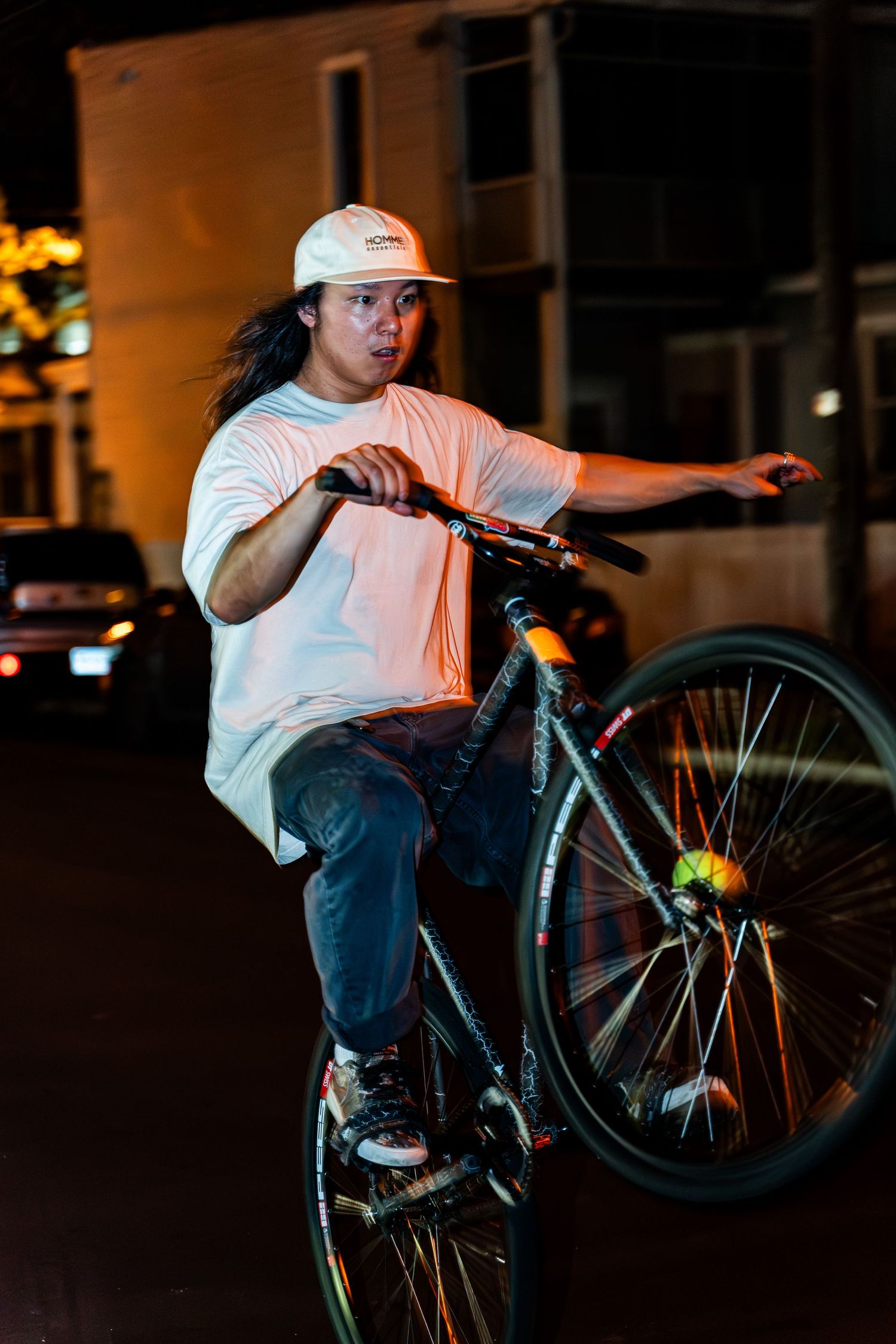 Urban cyclist performs wheelie trick on bike at night.