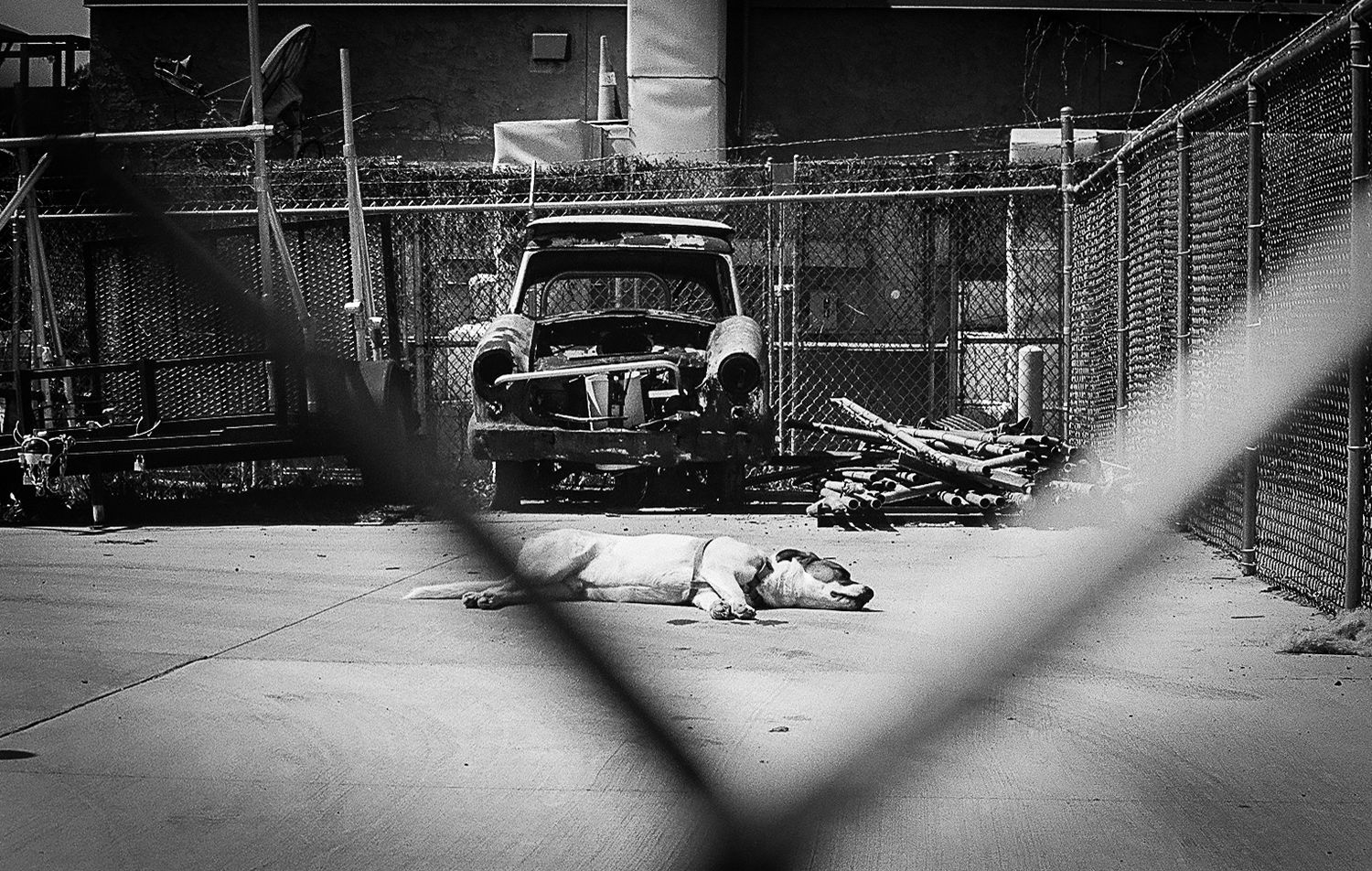 Black and white photograph of an old car in an abandoned industrial garage.