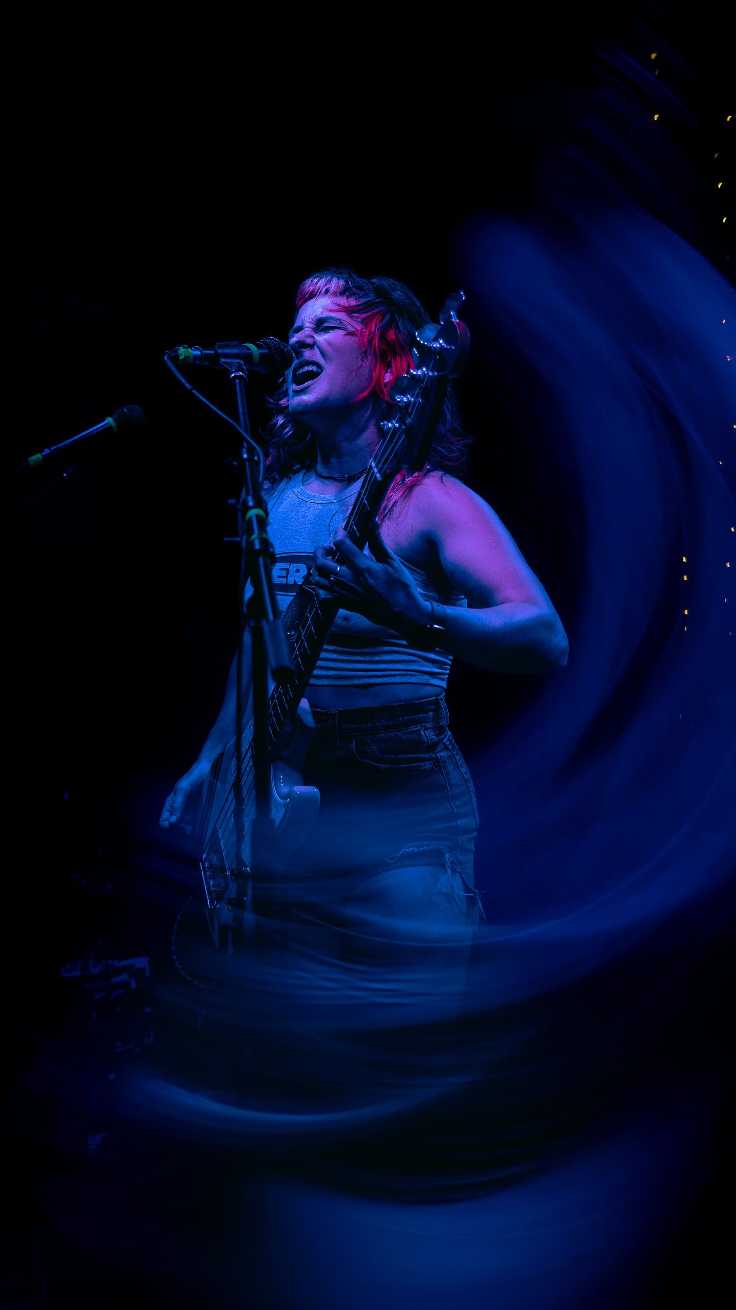 Musician performs passionately with intense emotion under dramatic blue stage lighting with blurred motion effects.