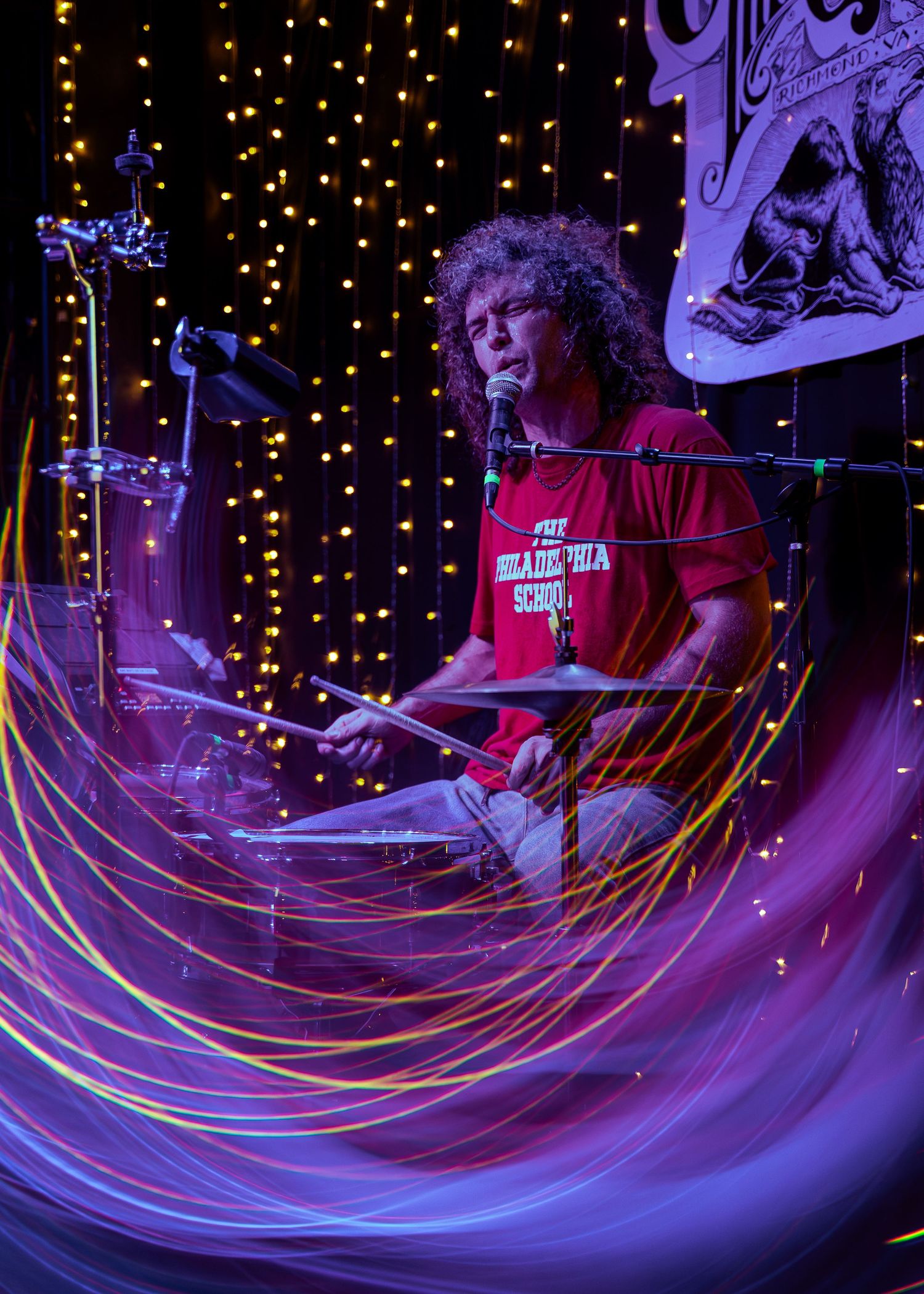 Long exposure photograph capturing light trails and motion blur against purple lighting and twinkle lights in dark setting.