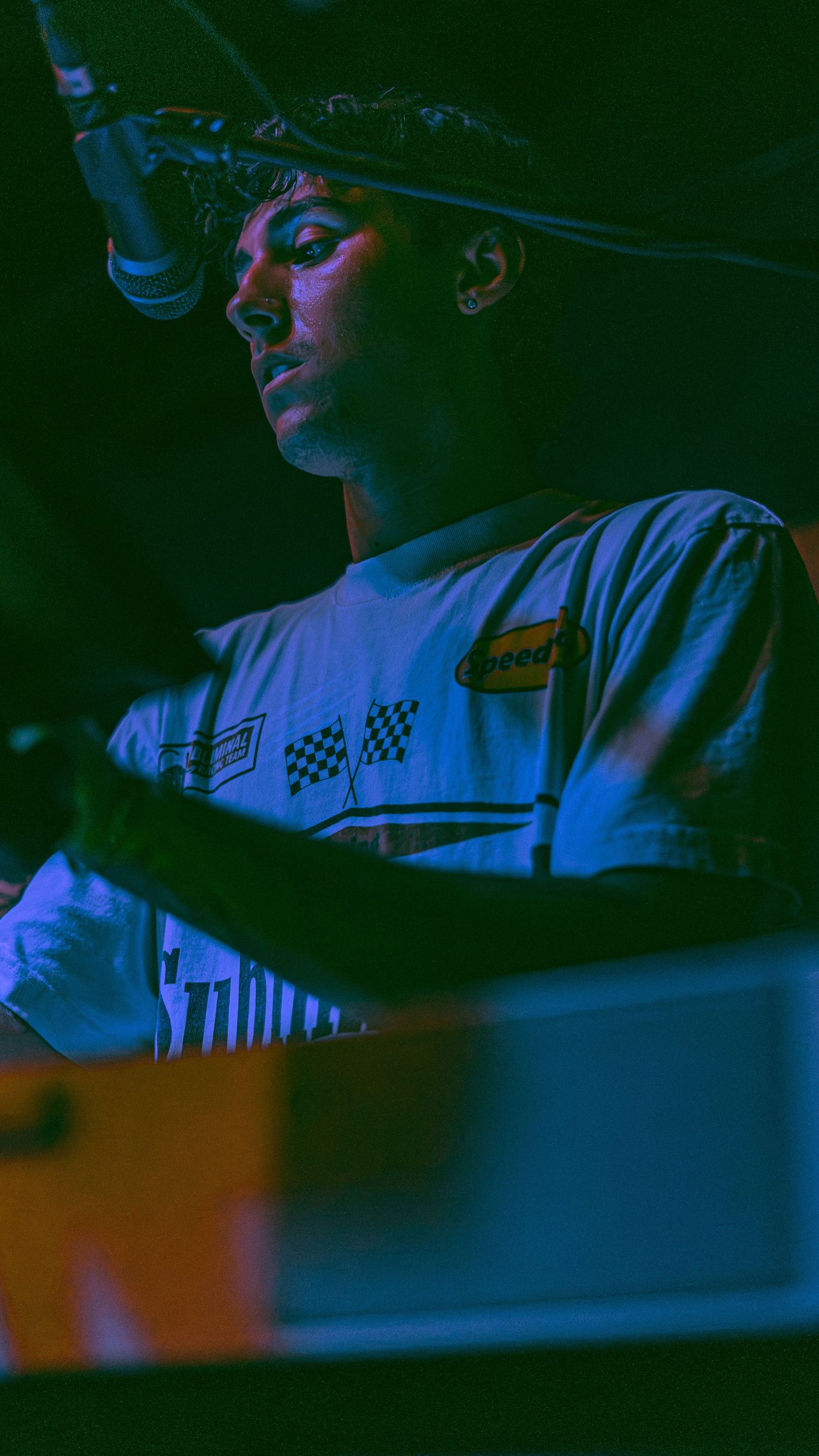 A person illuminated in dark blue lighting sits at a desk creating a moody cinematic atmosphere.