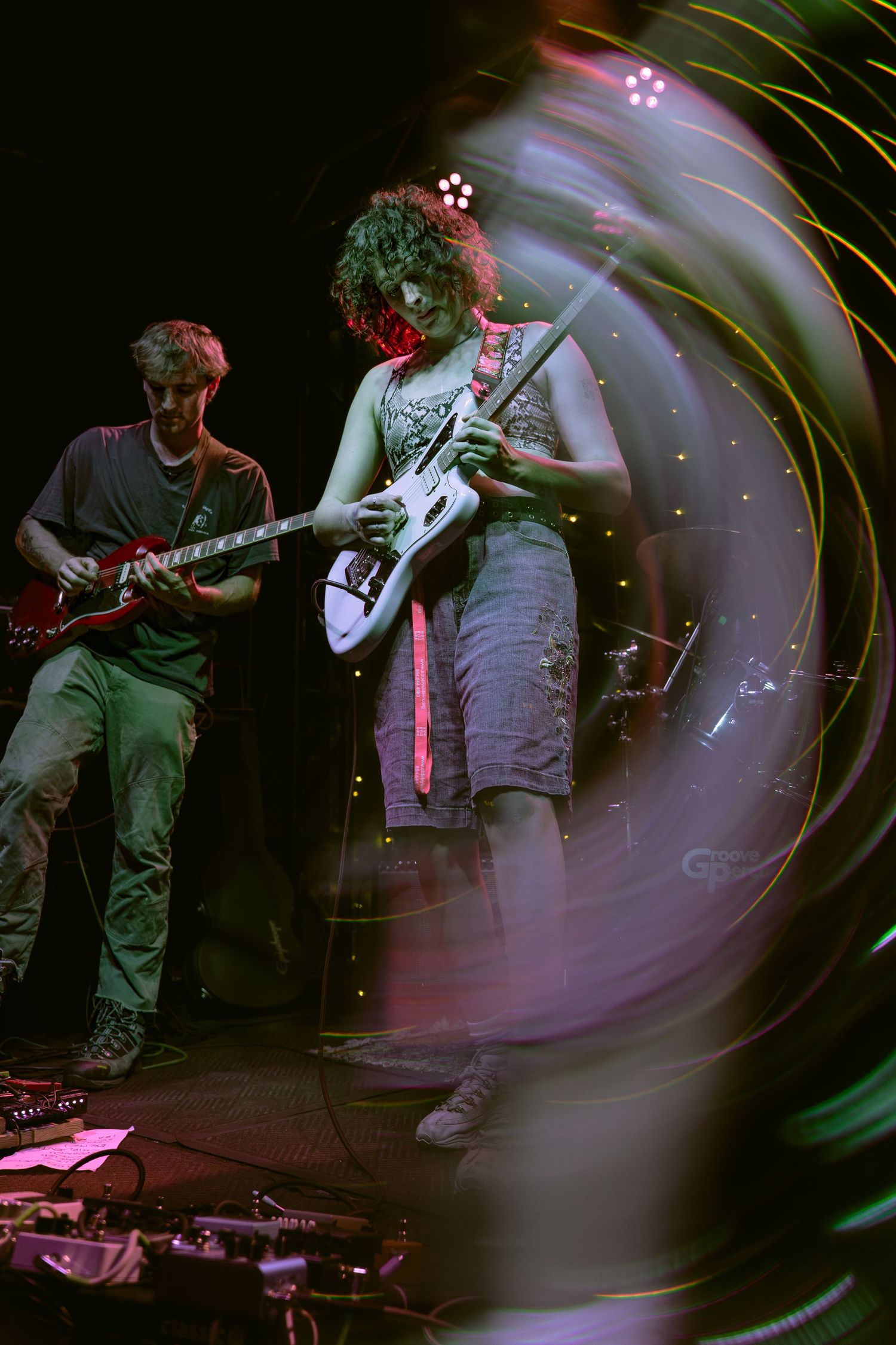 Multiple blurred action shots of musicians performing on stage with guitars in dramatic lighting.