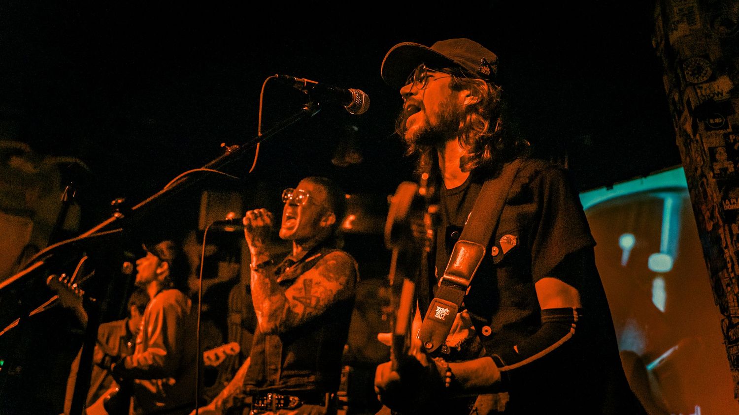 Three musicians performing on stage with guitars under moody lighting.