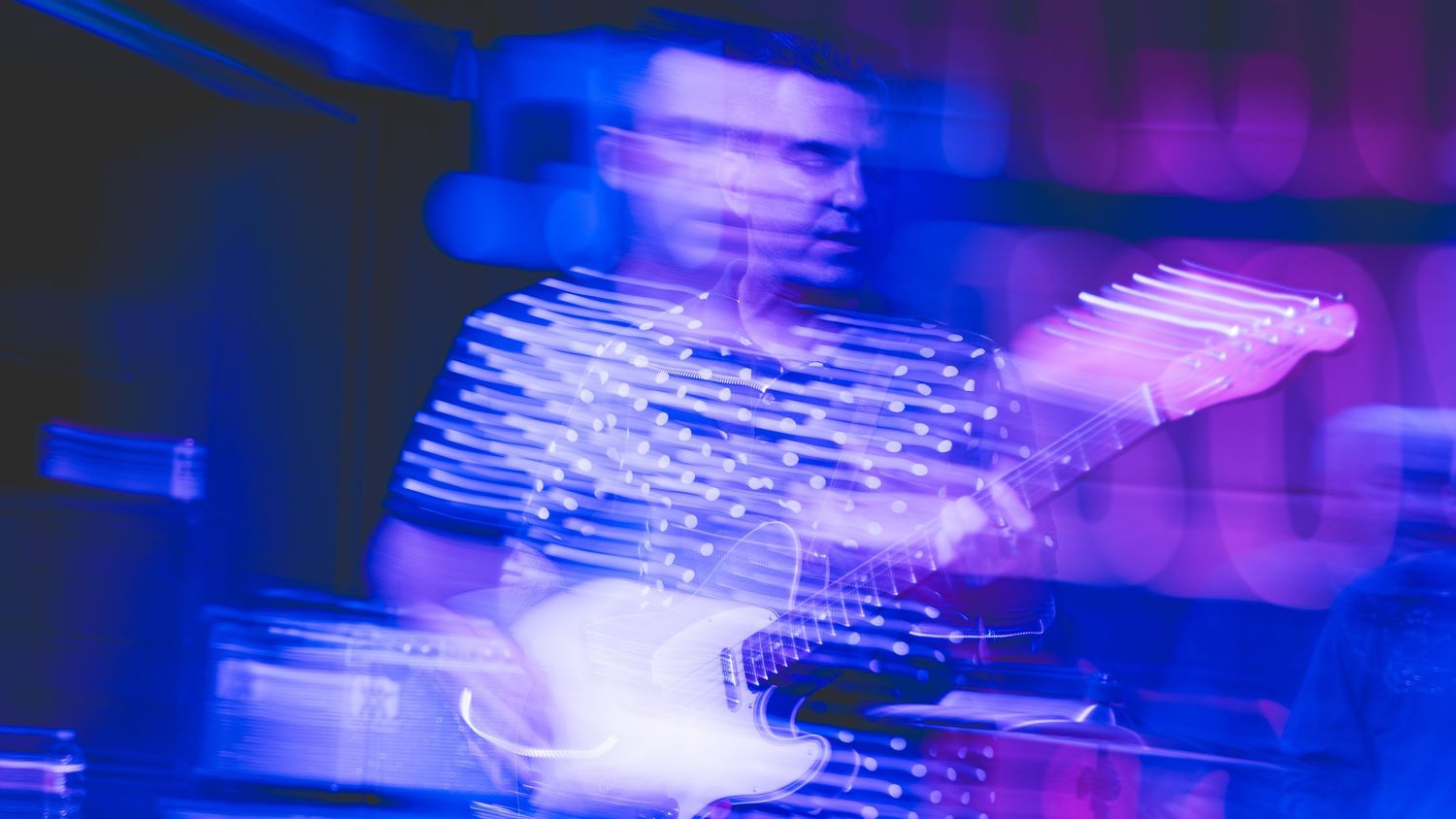 Artistic concert photography with blue and purple light trails creating ethereal effects.