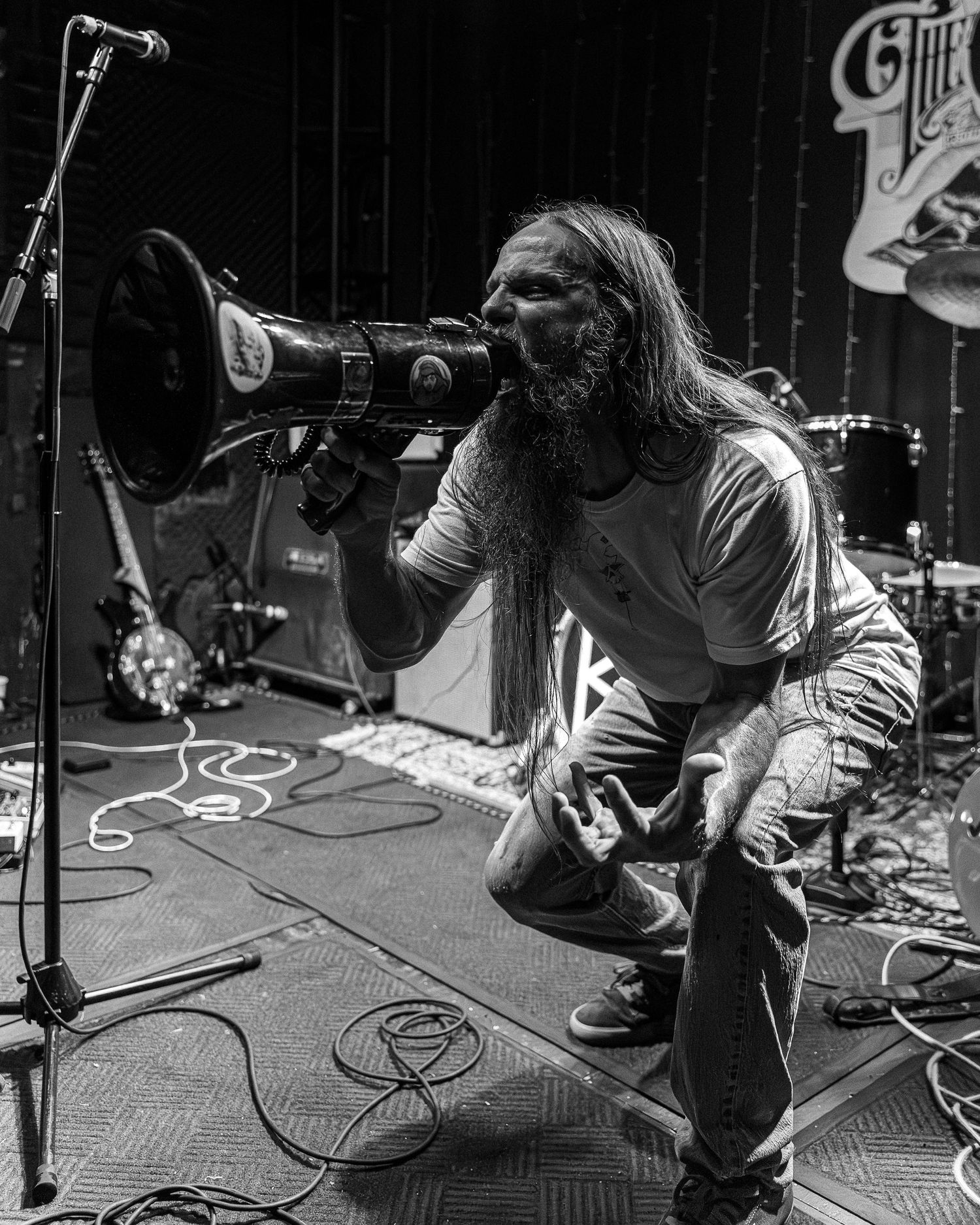 Black and white concert photo showing multiple musicians crouching down while playing instruments on stage.