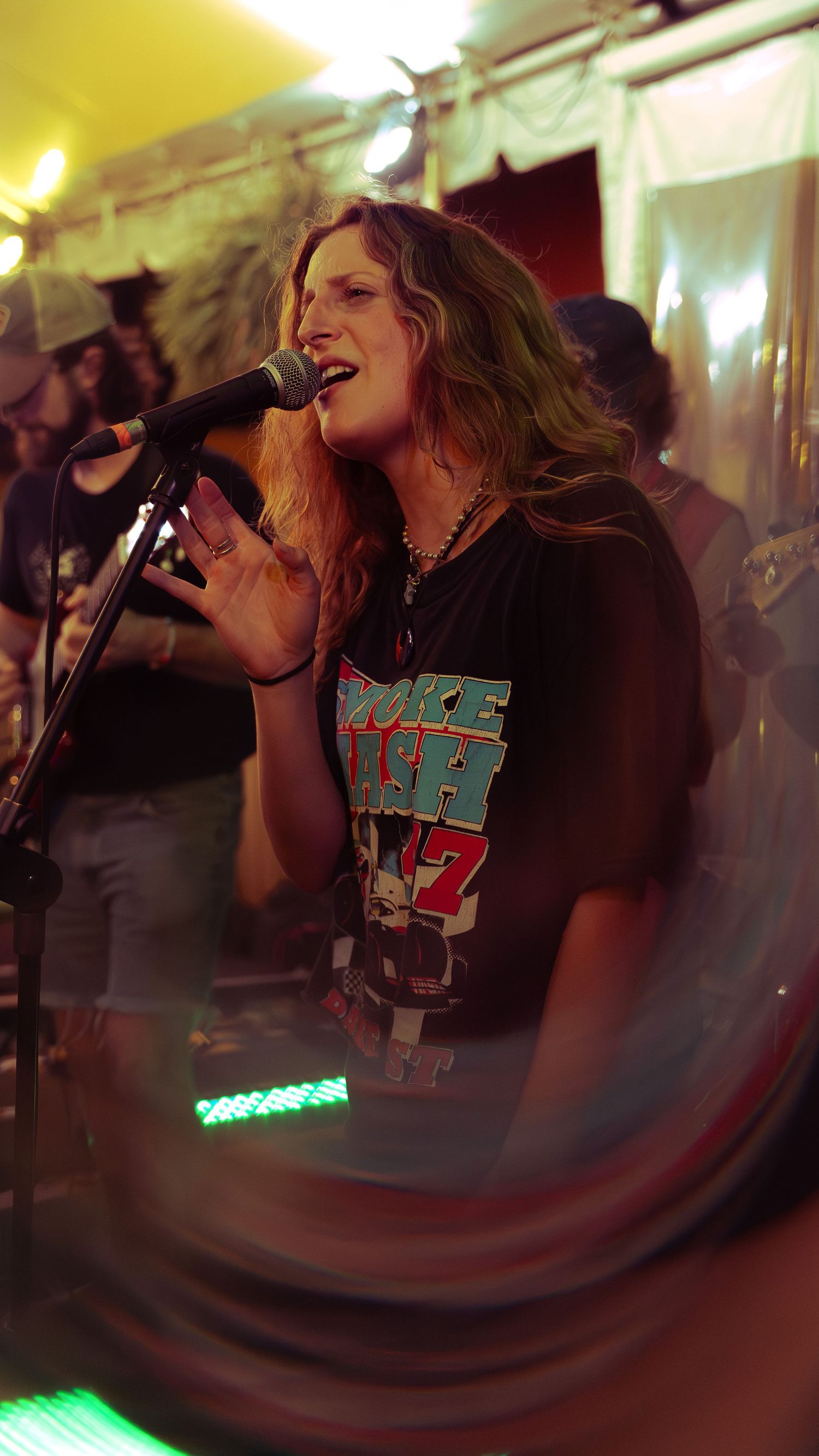 A passionate performer sings at a dimly lit concert venue with dramatic lighting effects creating an energetic atmosphere.