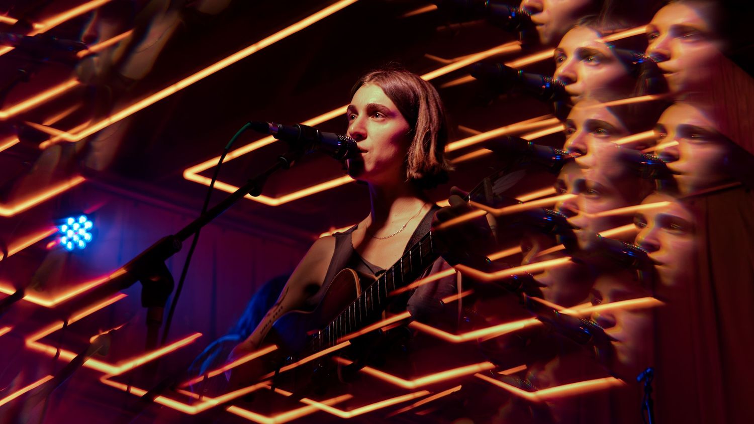 A symphony orchestra performs on stage with dramatic lighting and musicians playing various instruments in sync.
