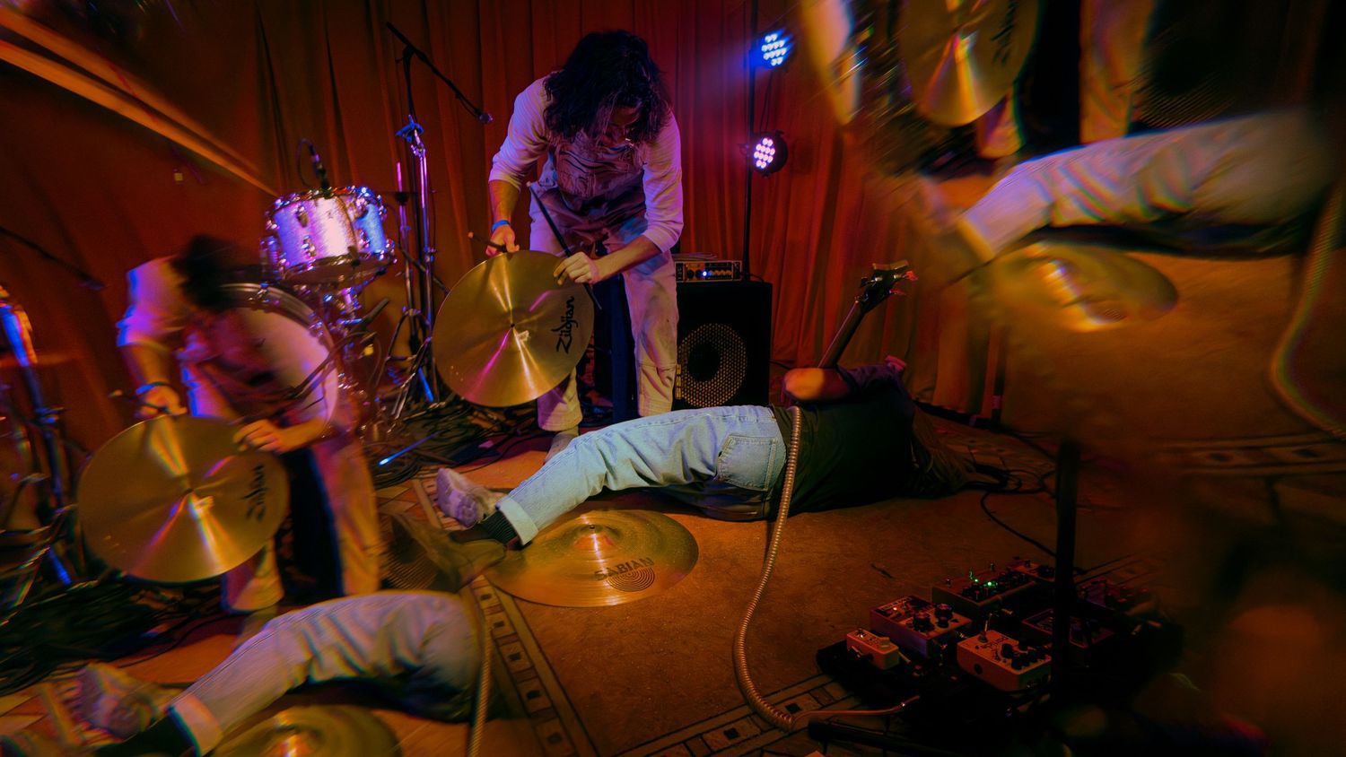 Performing musicians in a concert venue illuminated by colorful spotlights create an energetic concert atmosphere.