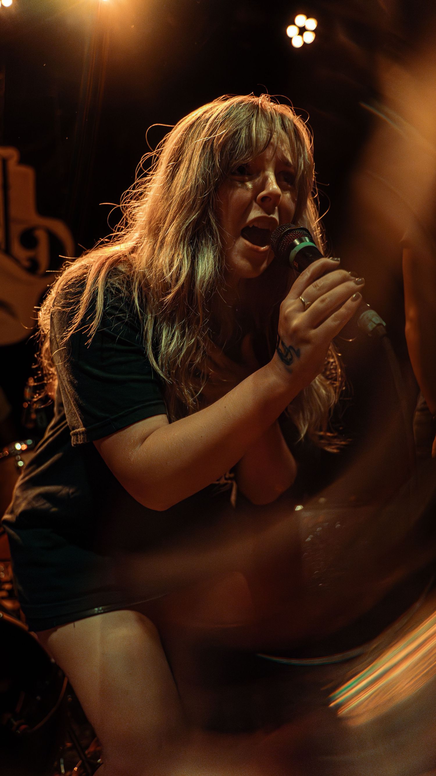 A dramatic silhouette of a singer performing on stage in dim lighting with energetic movement.