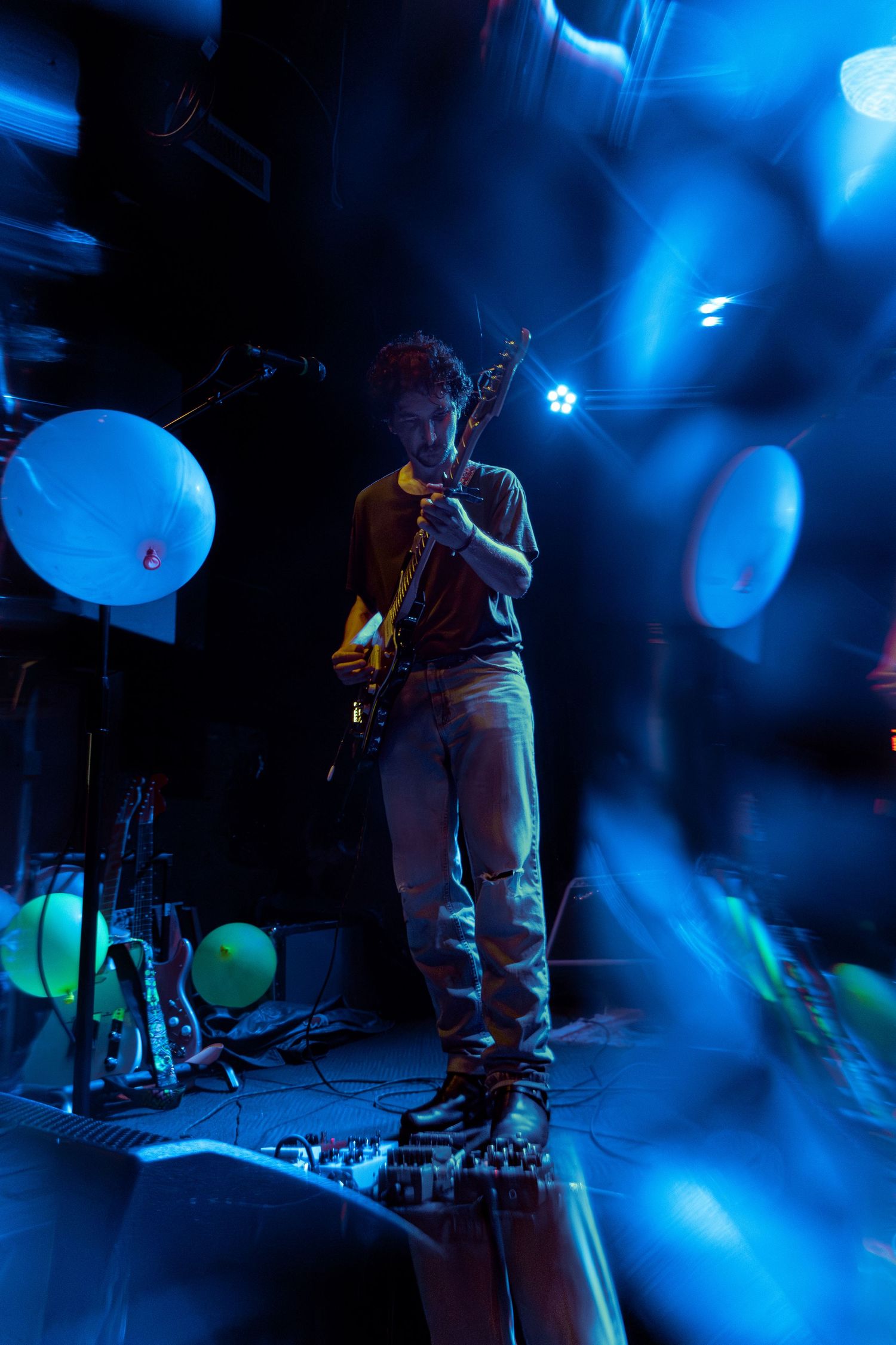 Concert stage bathed in dramatic blue lighting with musical instruments silhouetted in the atmospheric setting.