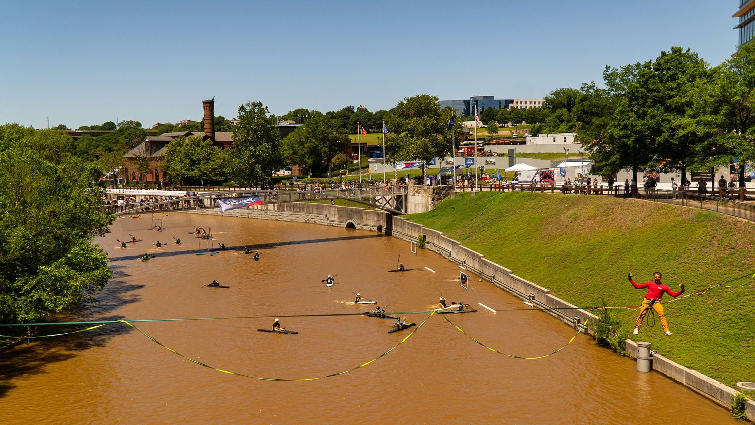 Aerial view of people relaxing along a muddy riverbank on a sunny day.