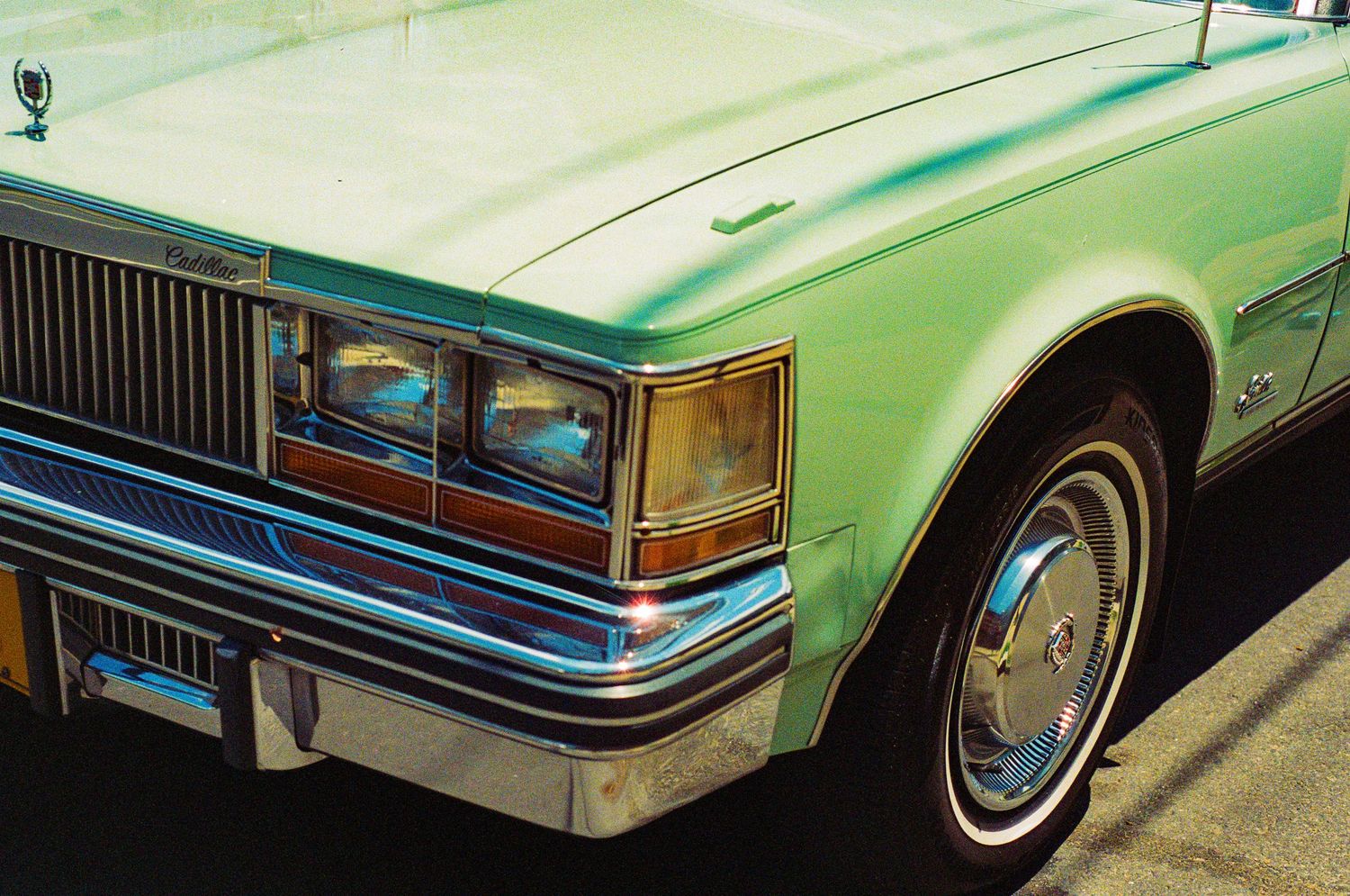 Front corner view of a vintage mint green Cadillac with chrome trim and distinctive headlight design.