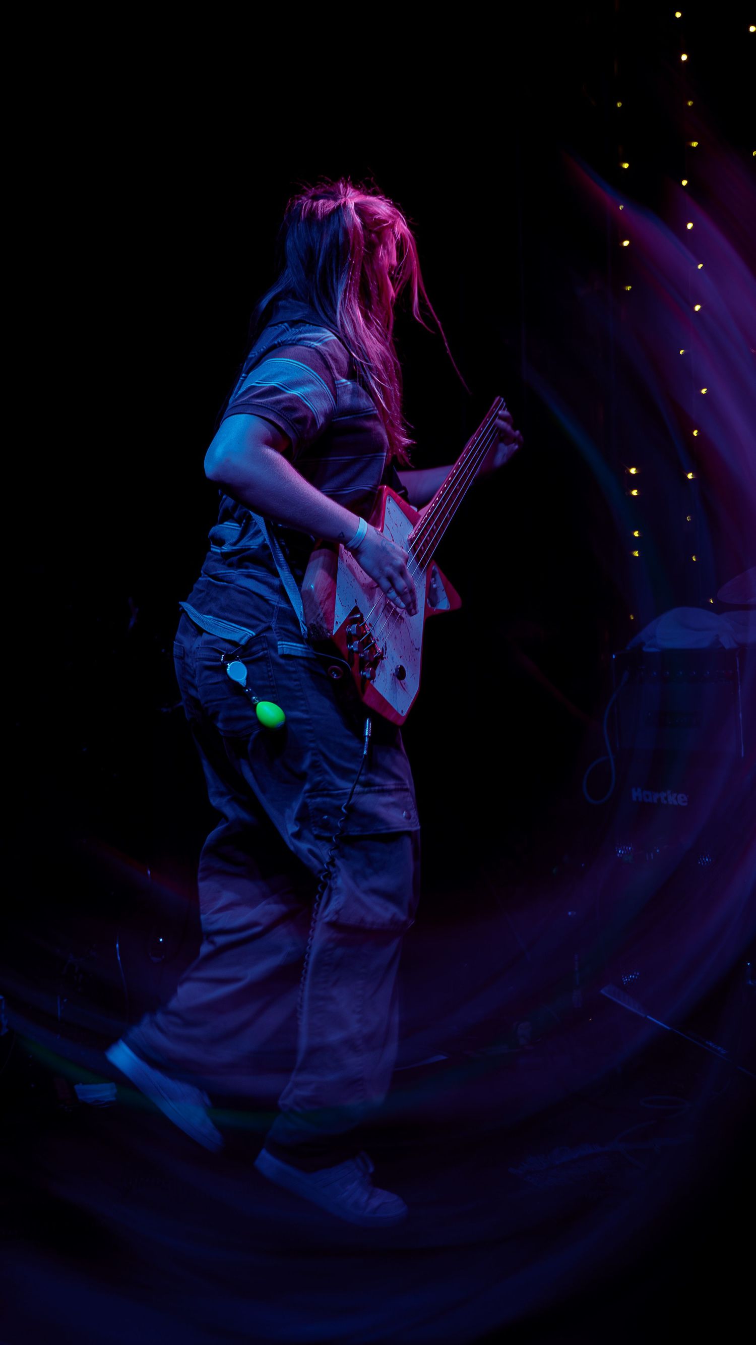 Abstract swirling motion blur photographs of a guitarist performing on stage in blue and purple lighting.