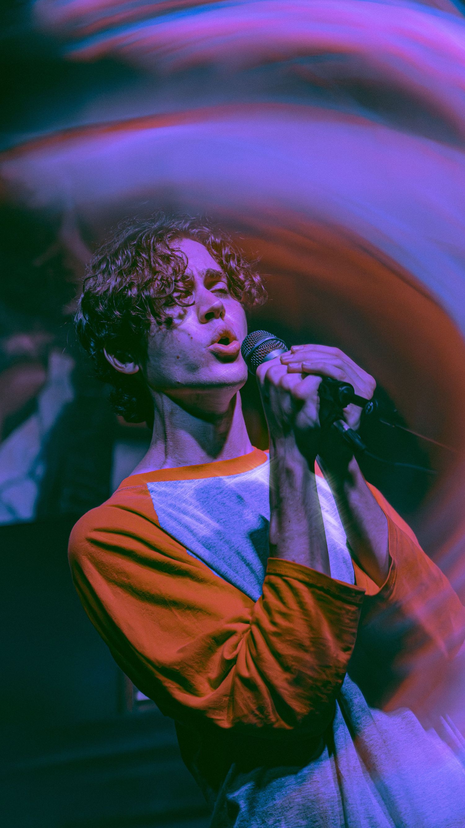 Artistic photo sequence showing person in orange and white clothing against dark background with purple lighting effects.