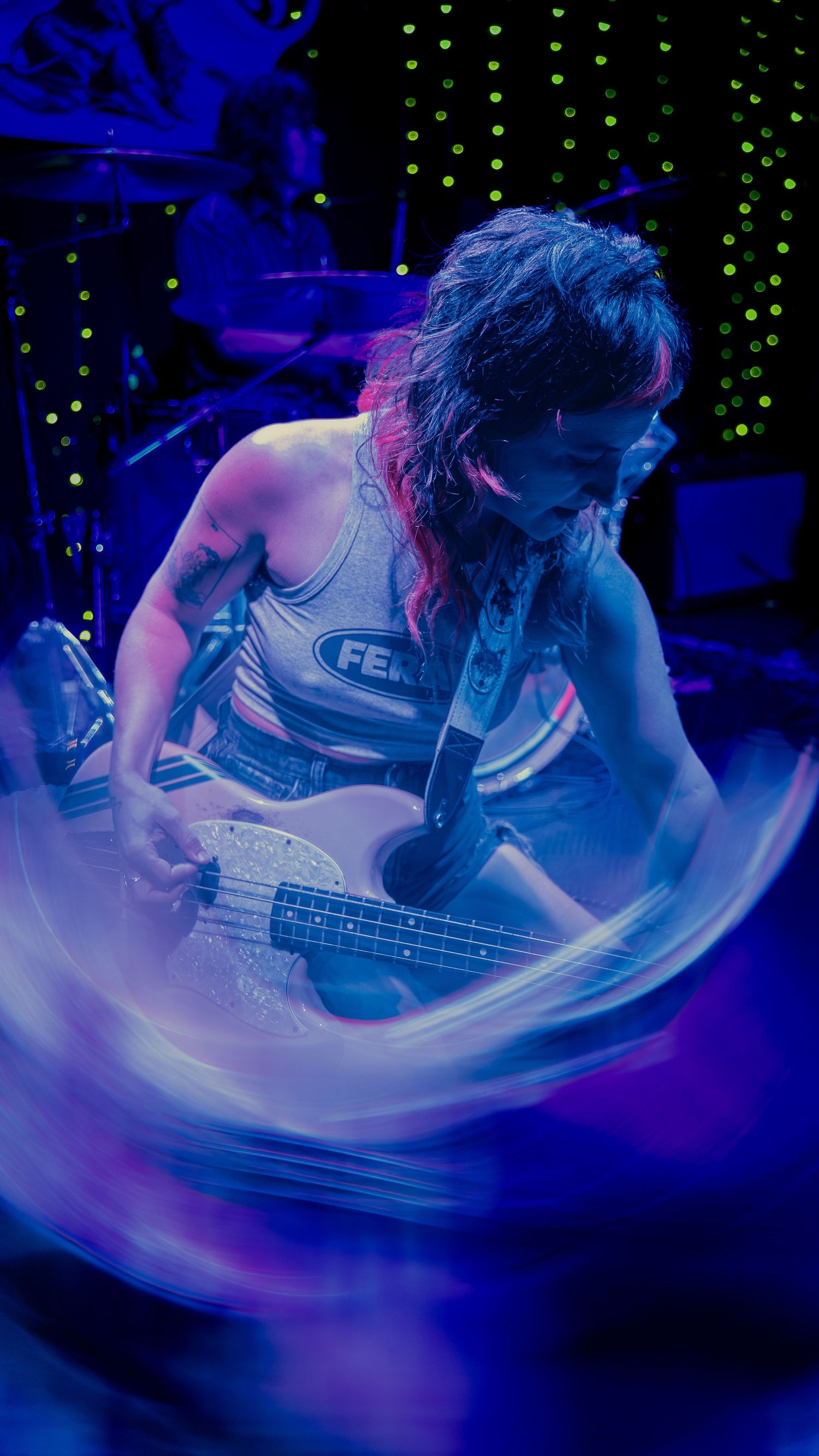 Musician performing on stage bathed in dramatic blue lighting with dynamic motion blur effects.