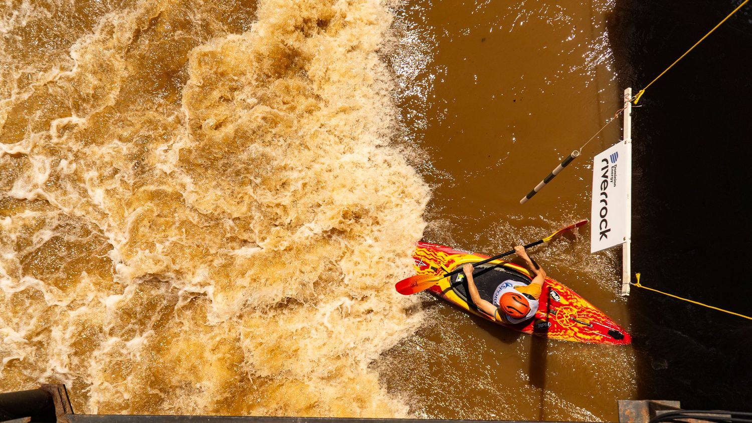 Athletes cross rushing brown water during extreme obstacle course race.