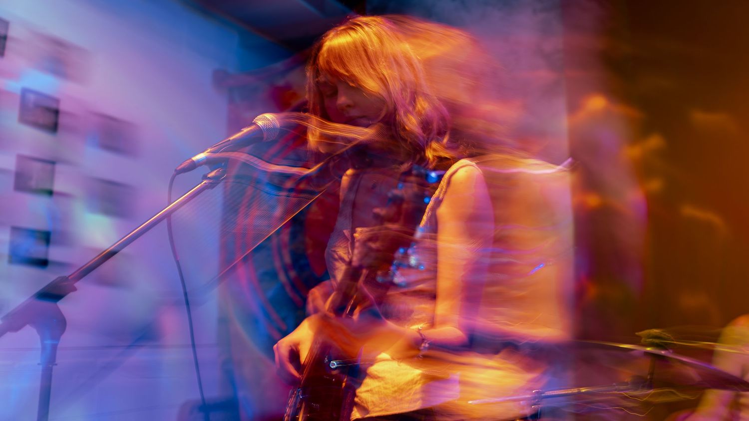 Long exposure concert photo with orange light trails creating artistic motion blur effects.