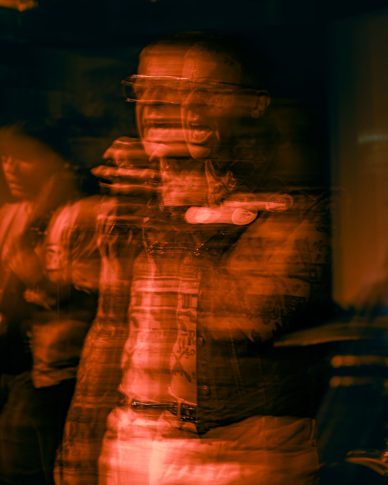Abstract blurred motion capture of performers in red lighting creating an ethereal effect on stage.