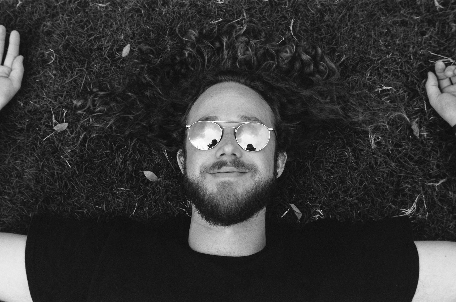 Overhead view of someone lying on grass with glasses in black and white.