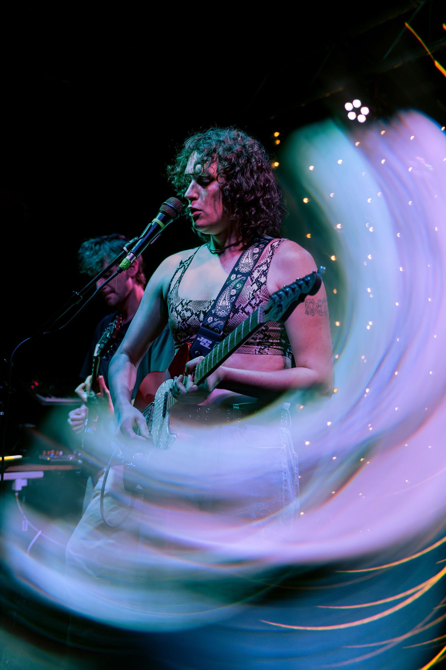 A dynamic performance captured with motion blur and colorful stage lighting creates a dreamy swirled effect.