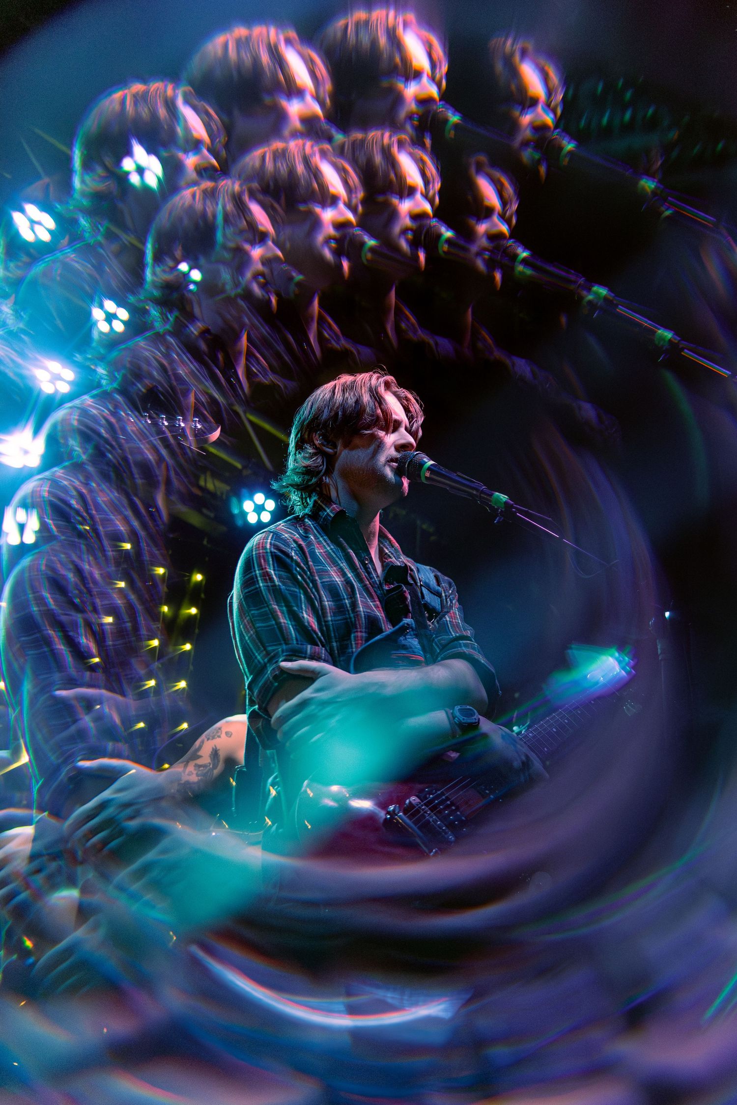 Motion-blurred concert scene with swirling colors of turquoise and purple lights creating a dynamic spiral pattern.