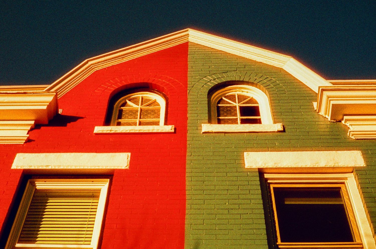 Red and green architectural facade with arched windows creating a vibrant color contrast.