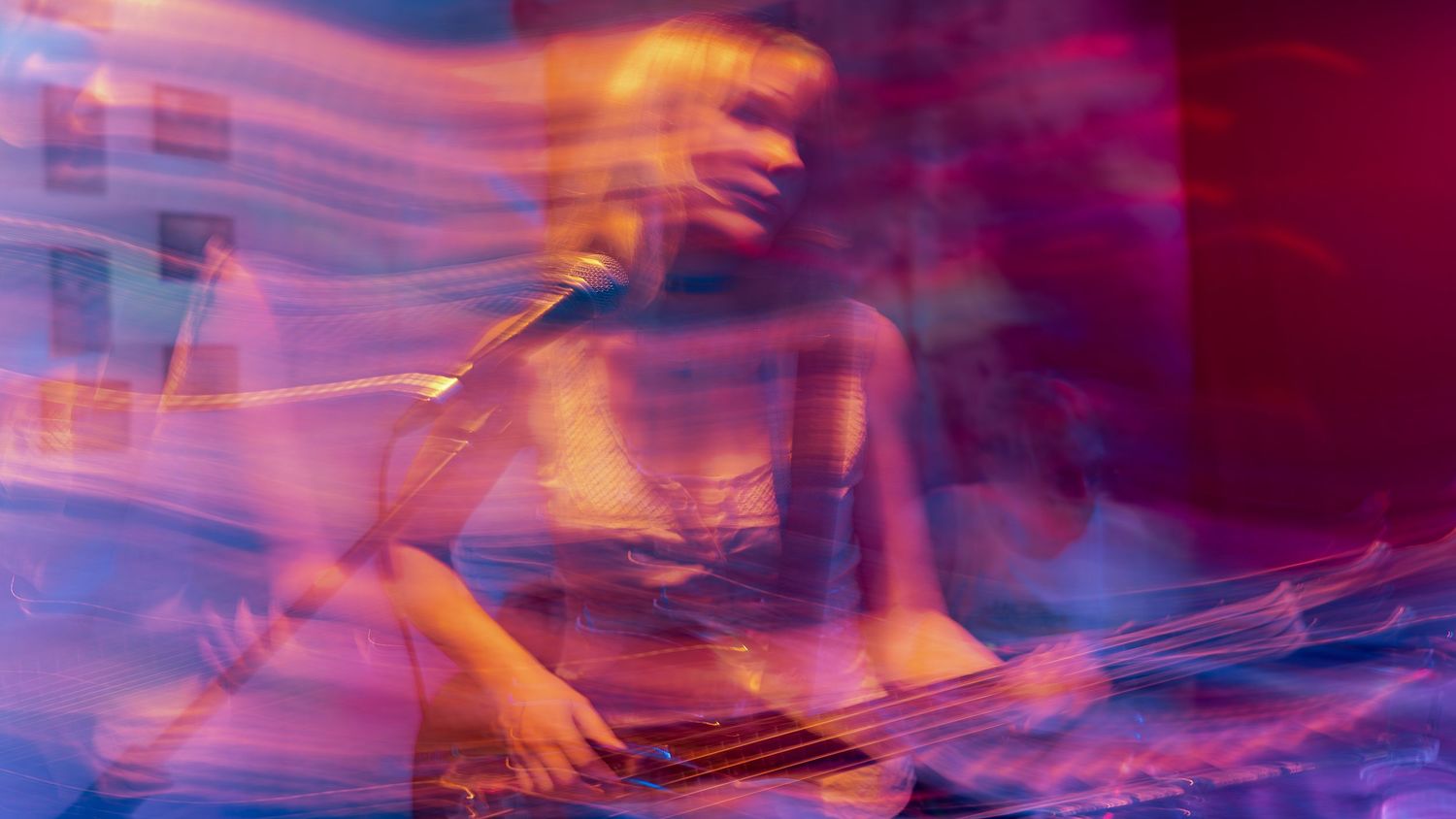 Abstract concert photography with purple and pink motion trails creating ethereal patterns.