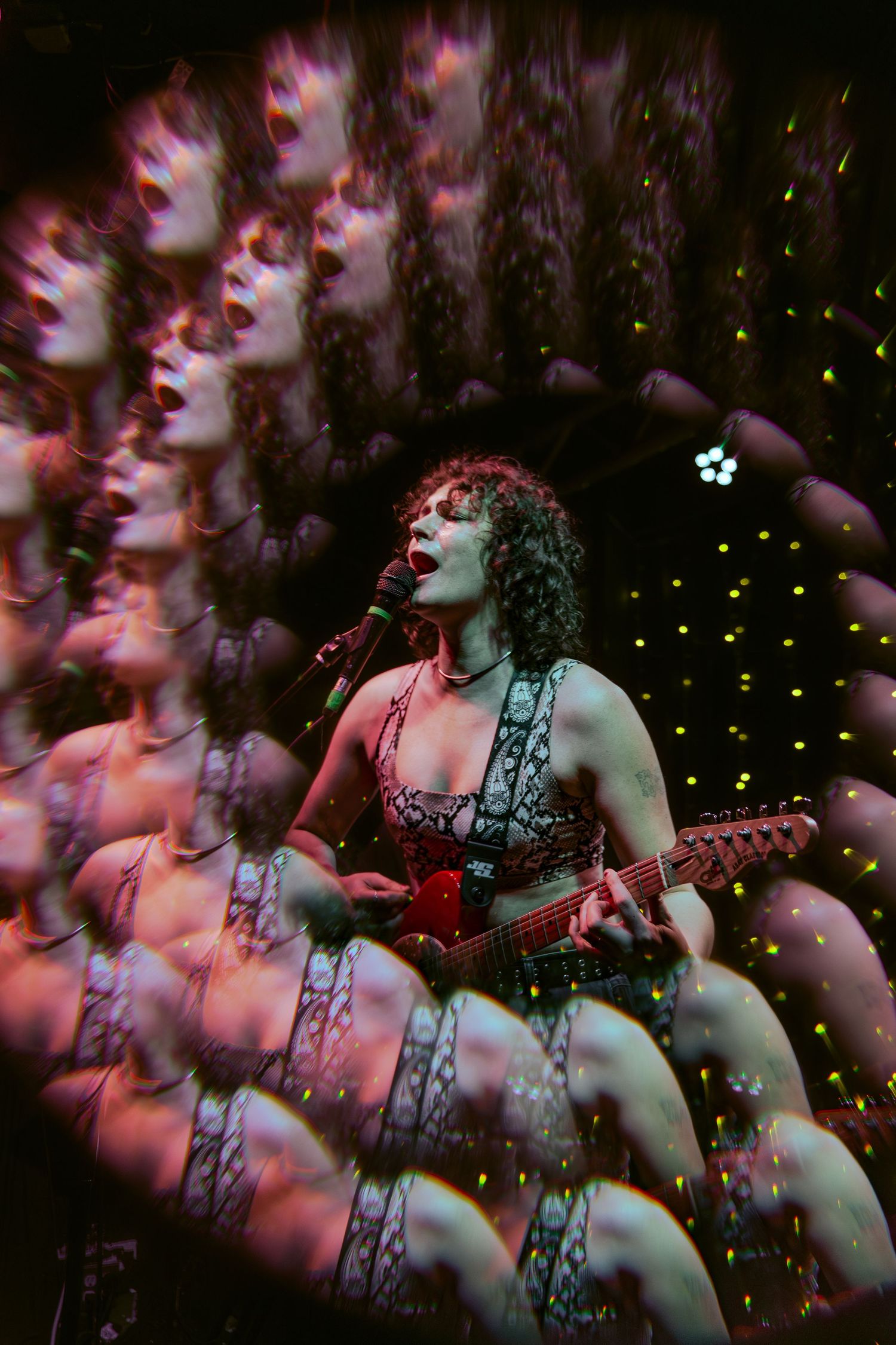 Multiple exposure photo of a performer singing and playing guitar on stage with dramatic red lighting effects.