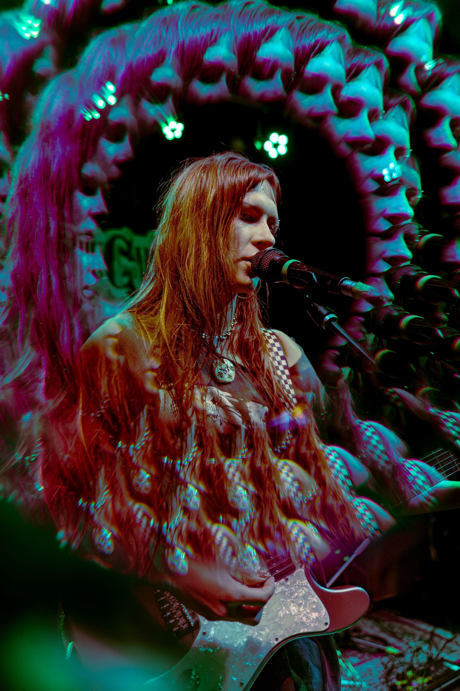 Psychedelic concert scene overlaid with vibrant turquoise and magenta colors creating a dreamy atmospheric effect.