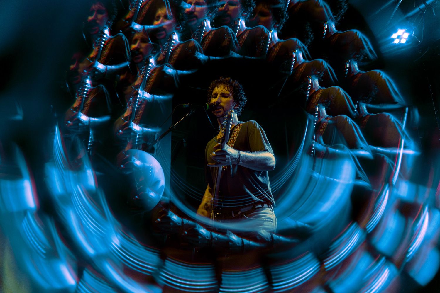 Blue smoke swirls in a dynamic spiral pattern creating an ethereal abstract light effect against a dark background.
