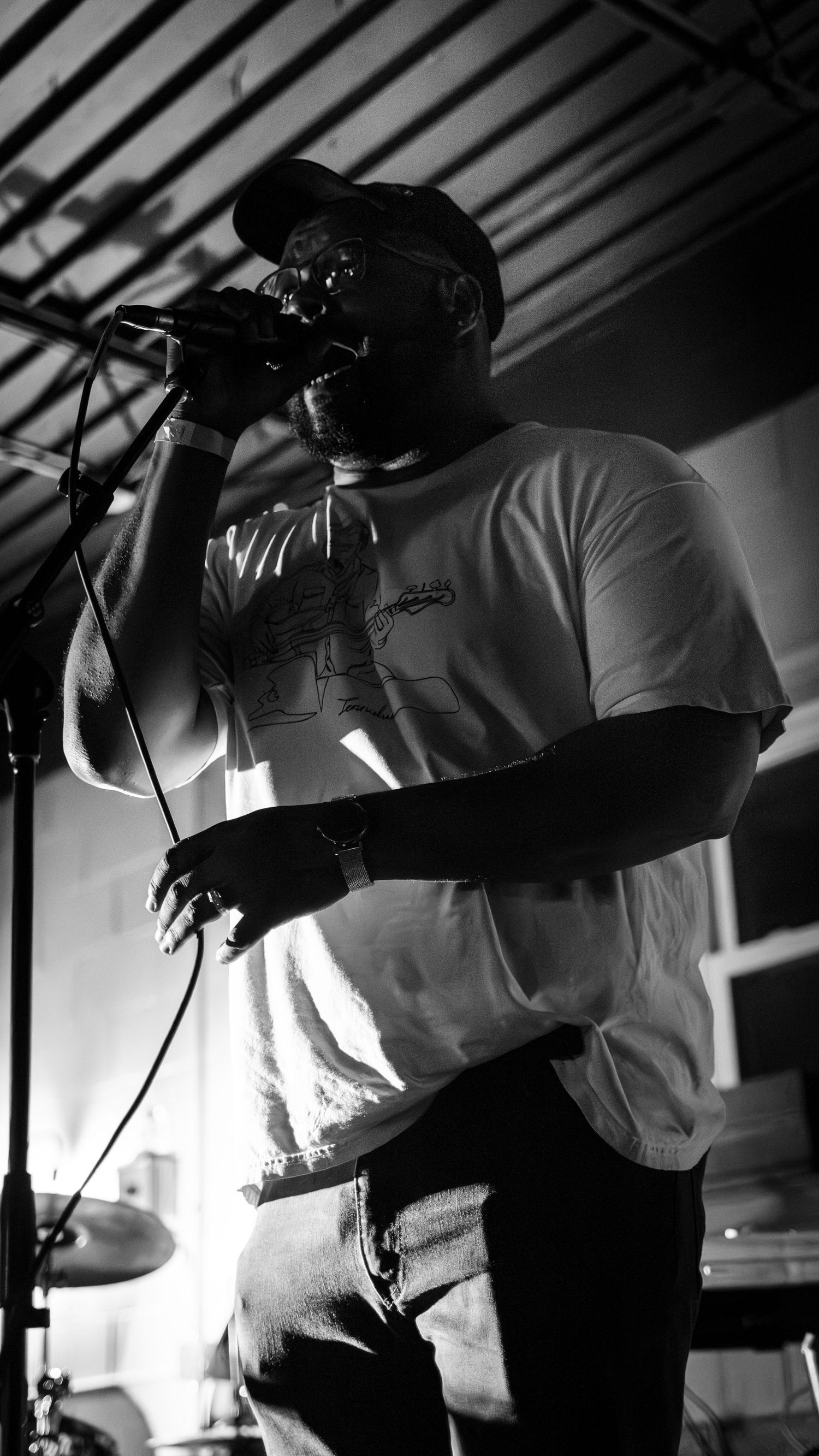 Silhouetted performer playing trumpet on stage in black and white.