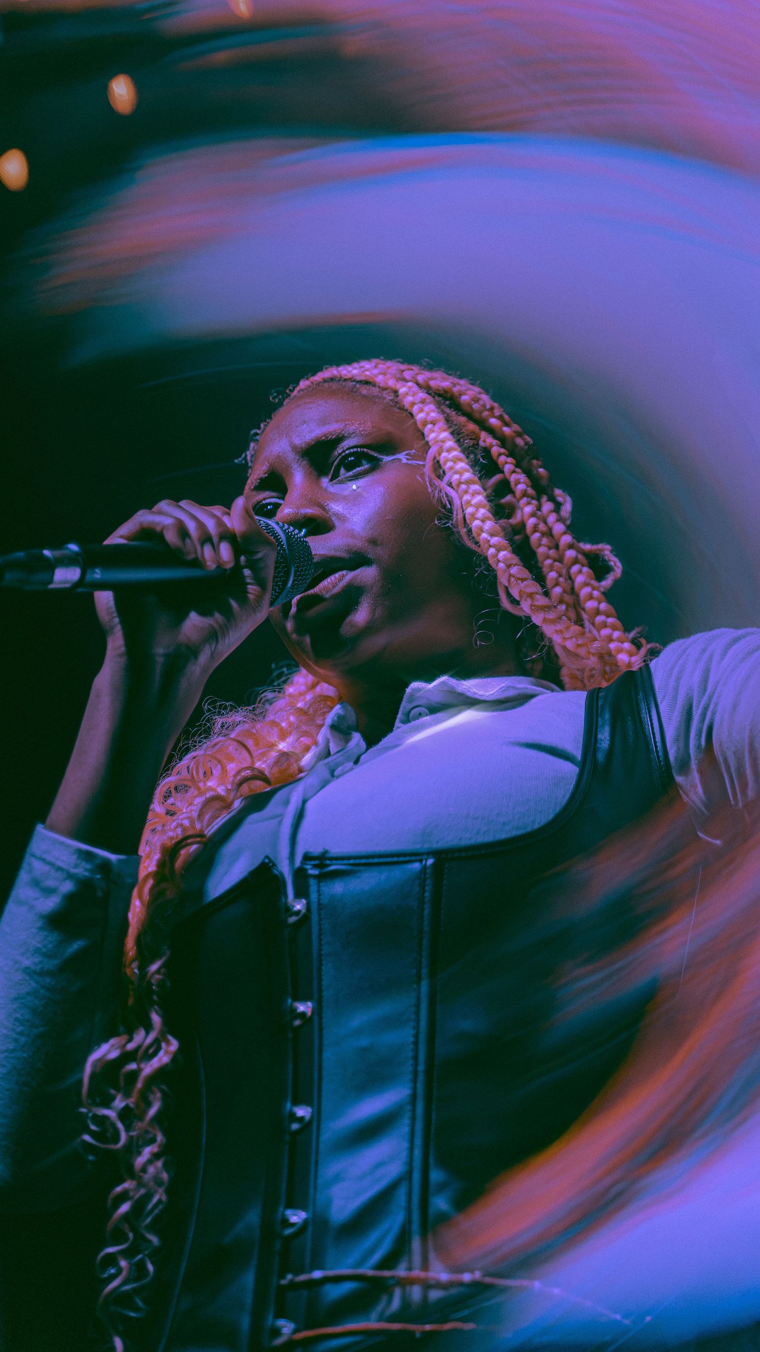 Artistic performance photos with purple and blue lighting effects show a singer with braided hair performing on stage.