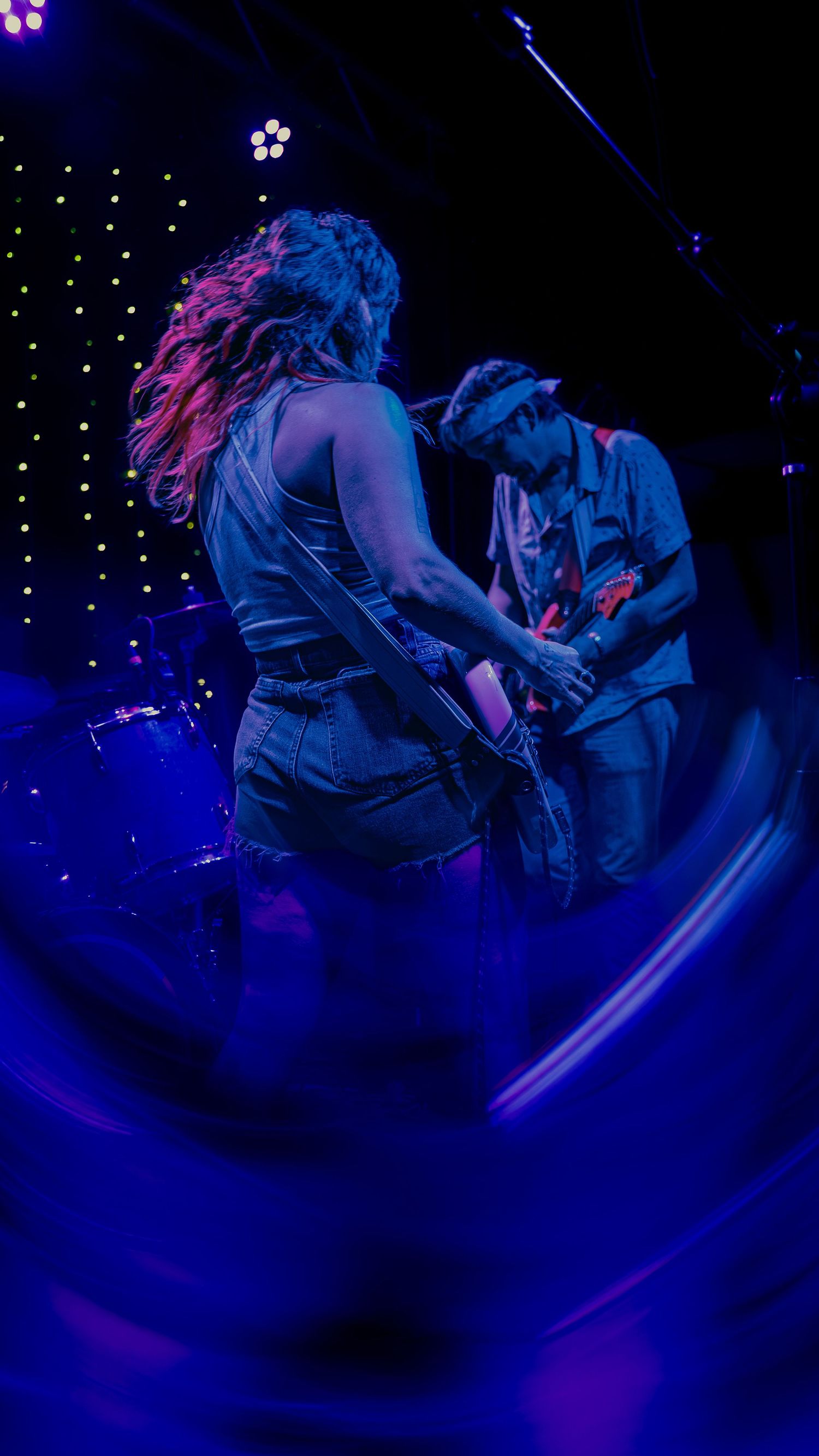 Dynamic dance performance captured in dark blue lighting with swirling motion effects and starlit backdrop.