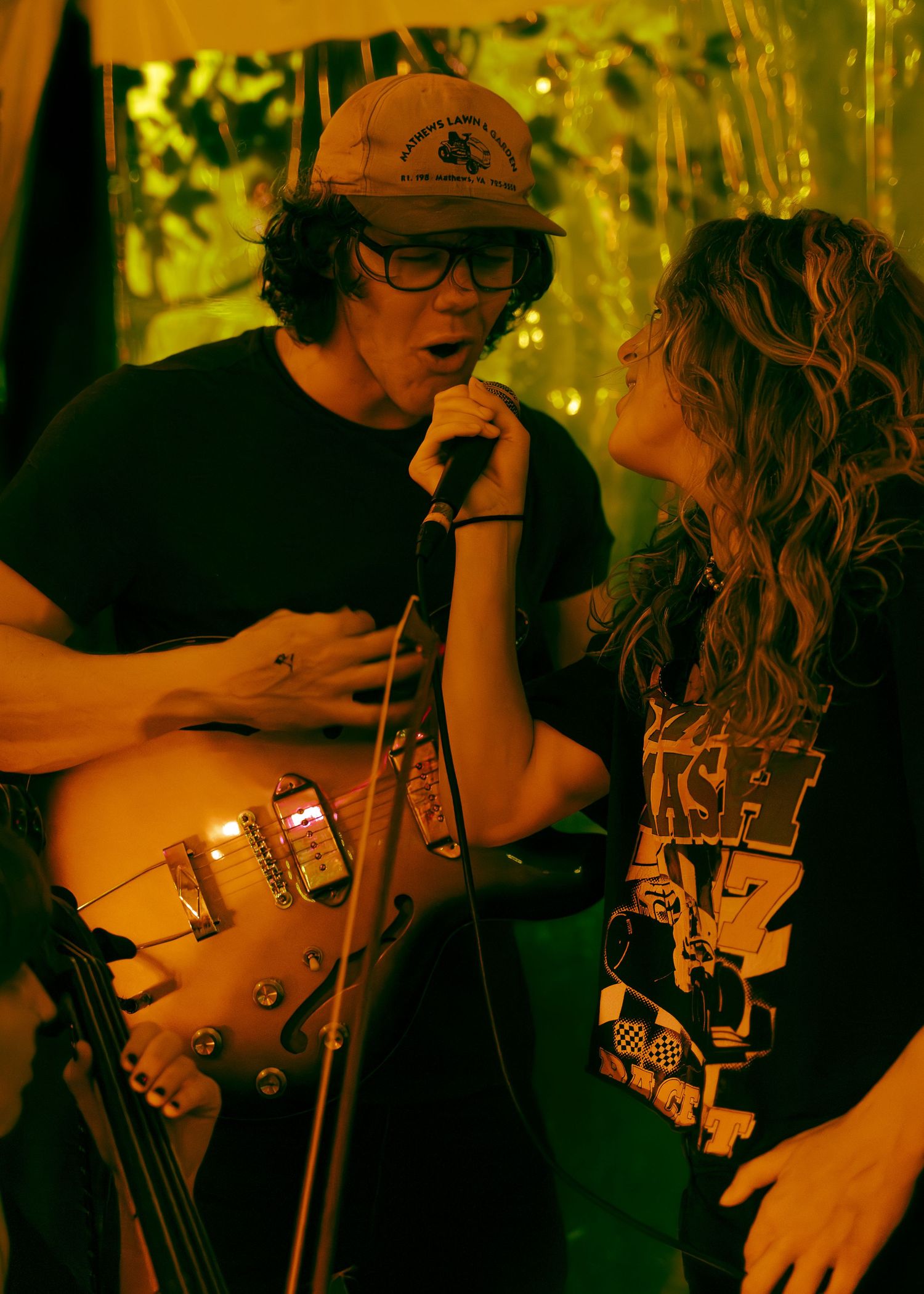 Musicians on stage bathed in golden lighting performing intimate acoustic duet during live show.