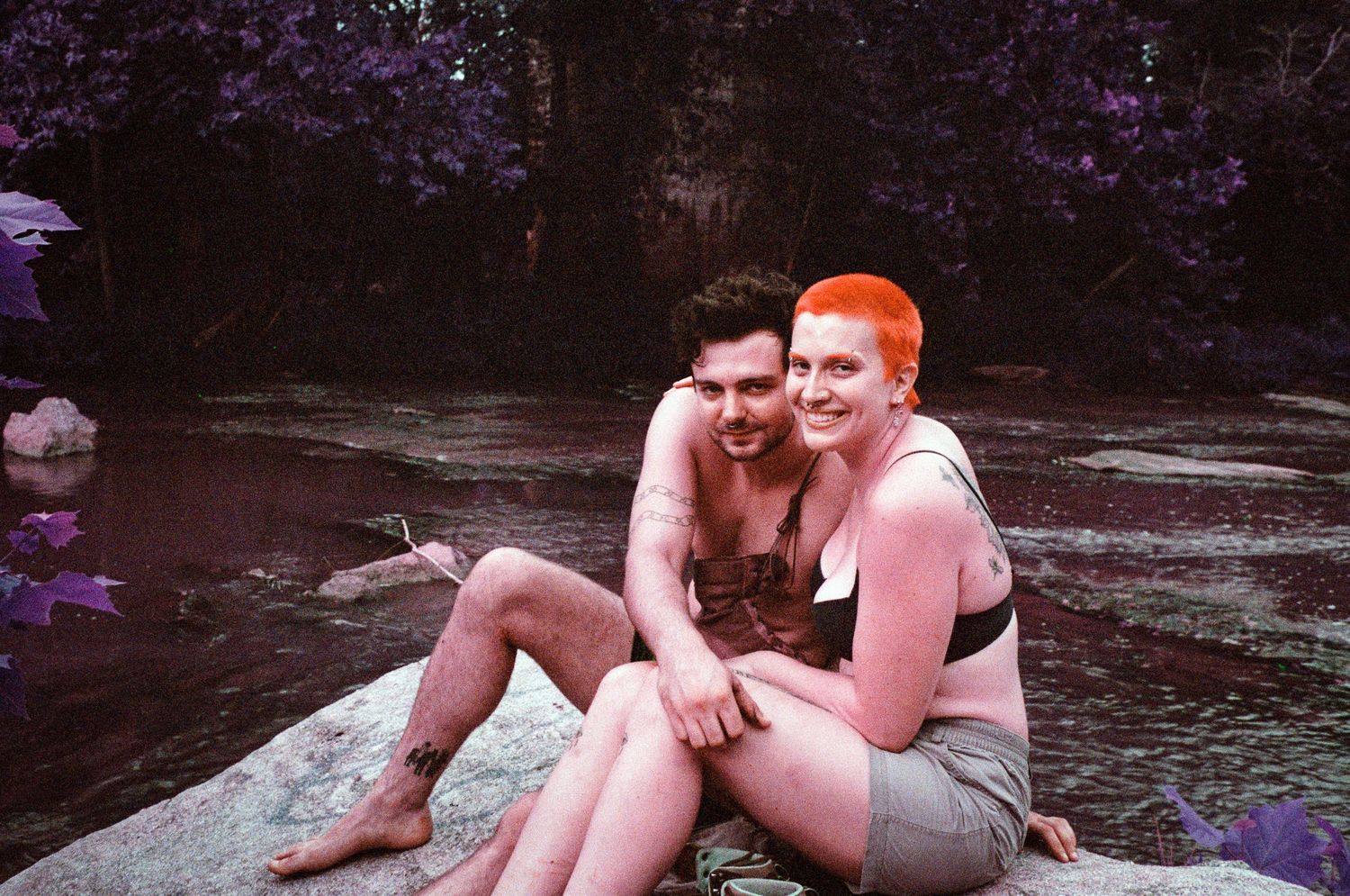People relaxing by a natural water feature on a summer day.