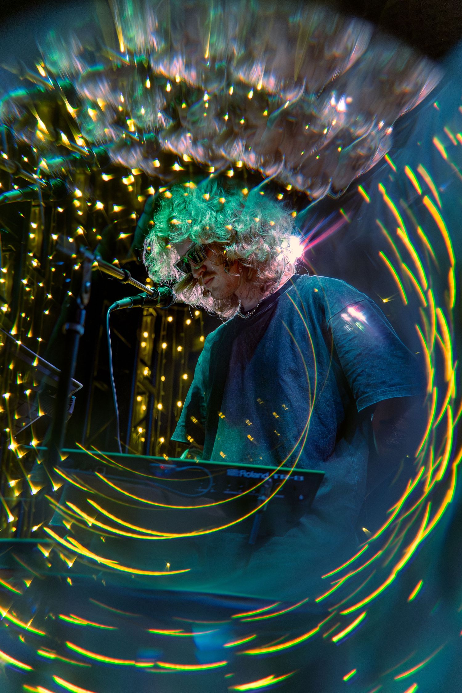 Long exposure photo shows dynamic light trails swirling in circular patterns against a dark blue background with bokeh effects.