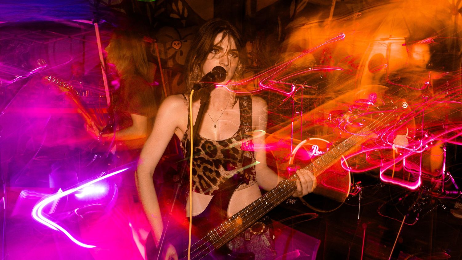 Rock musician performing with guitar amid vivid purple and orange light trails.